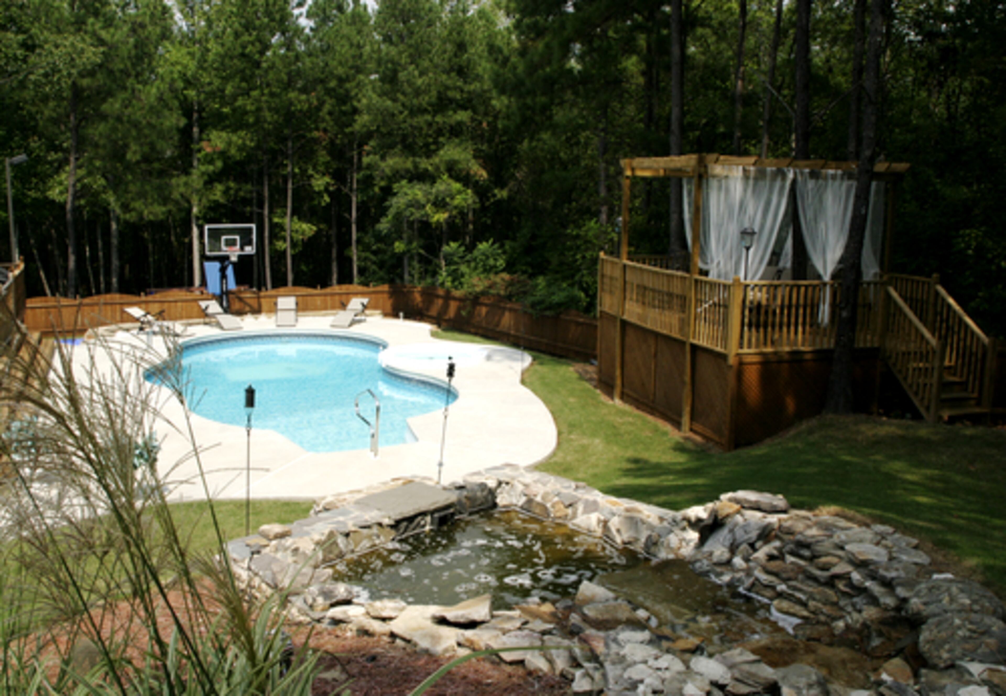 The Parkers' love for entertaining continues outside. The backyard includes a swimming pool, waterfall, hot tub and basketball court. On the other side of the pool is an elevated deck/DJ booth with flowing white curtains.