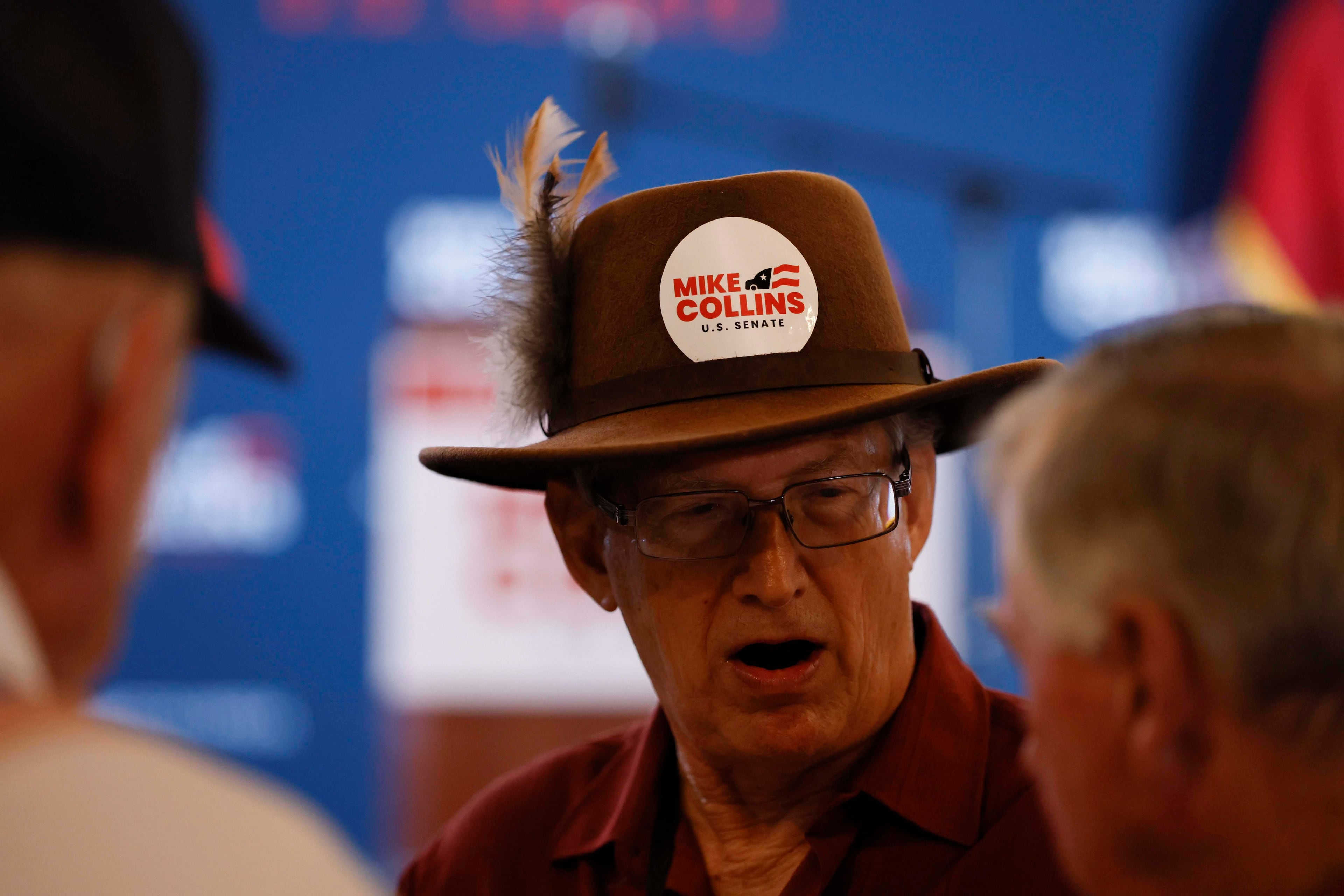 Will Trexler of Henry County wears a U.S. Rep. Mike Collins sticker while talking to attendees at the runoff election watch party at Seven Oaks Manor in Jackson, Georgia, on Tuesday, June 16, 2026. (Miguel Martinez/AJC)