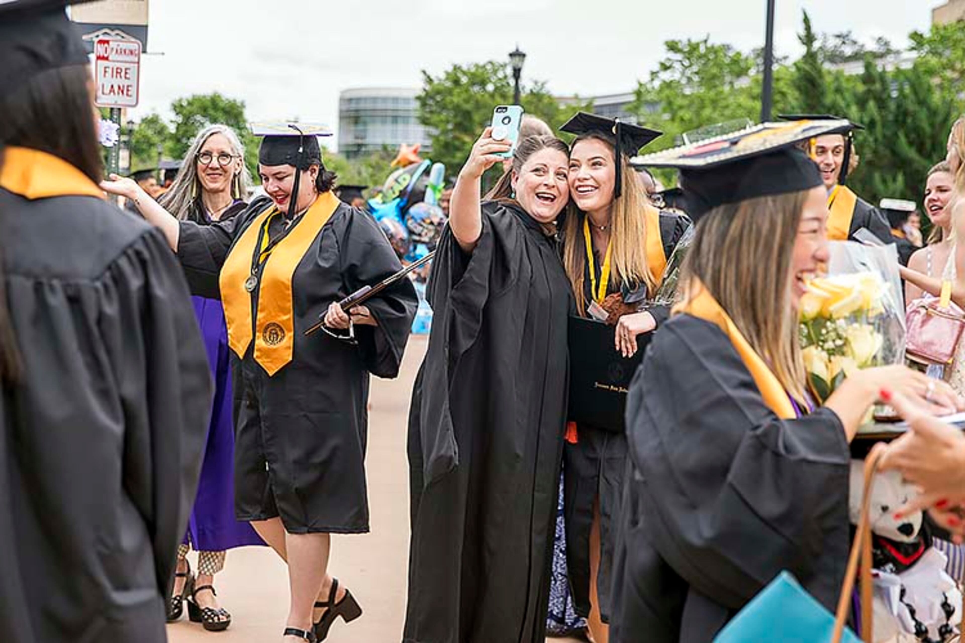 Kennesaw State University Prof. Amanda Wansa Morgan (center) takes a selfie with KSU alumnus Shannon Murphy (right) following the 223rd Kennesaw State University commencement ceremony at the convocation center on the university's main campus in Kennesaw, Thursday, May 9, 2019.