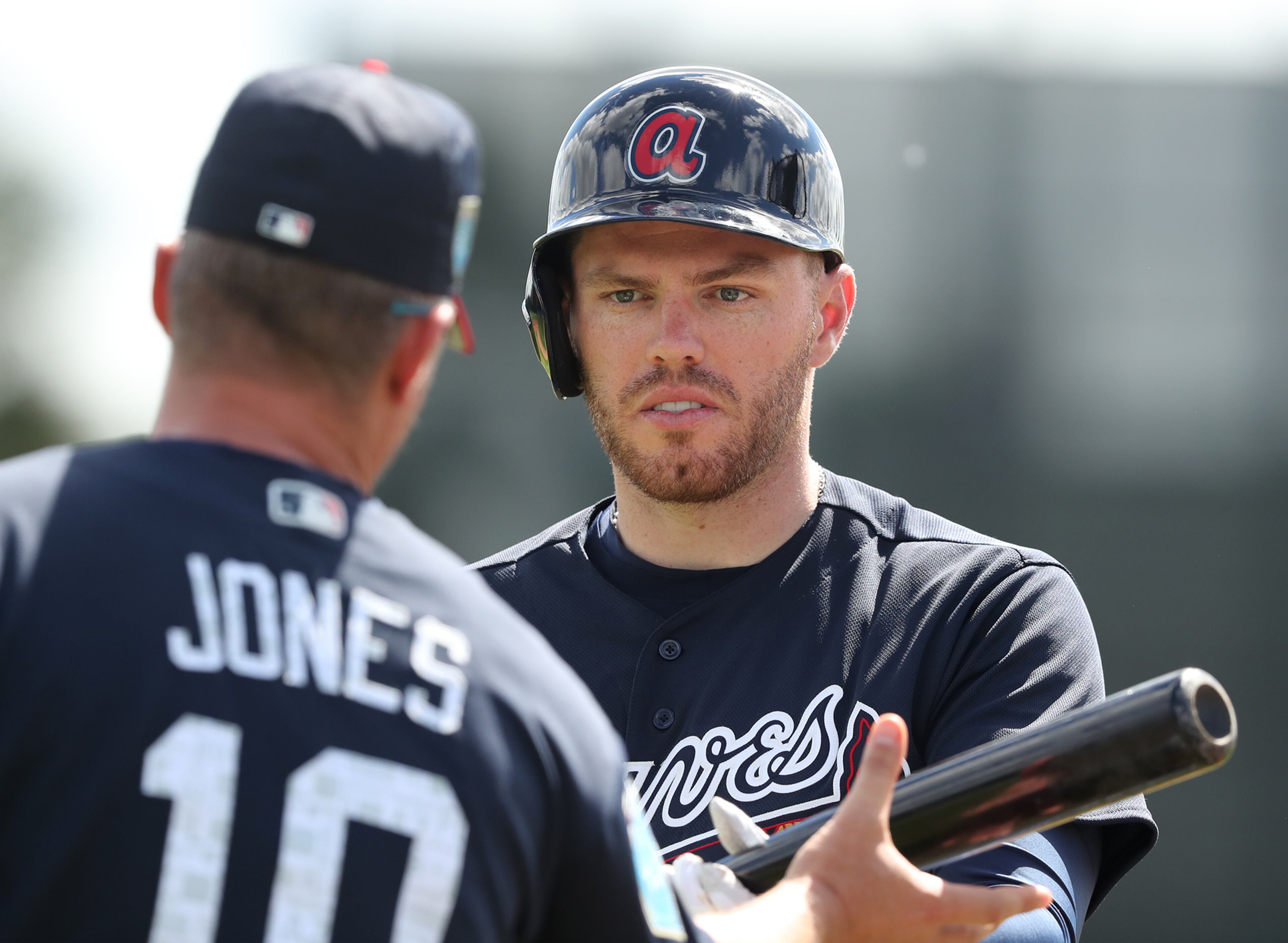 Chipper Jones checks out Freddie Freeman's bat during batting practice.