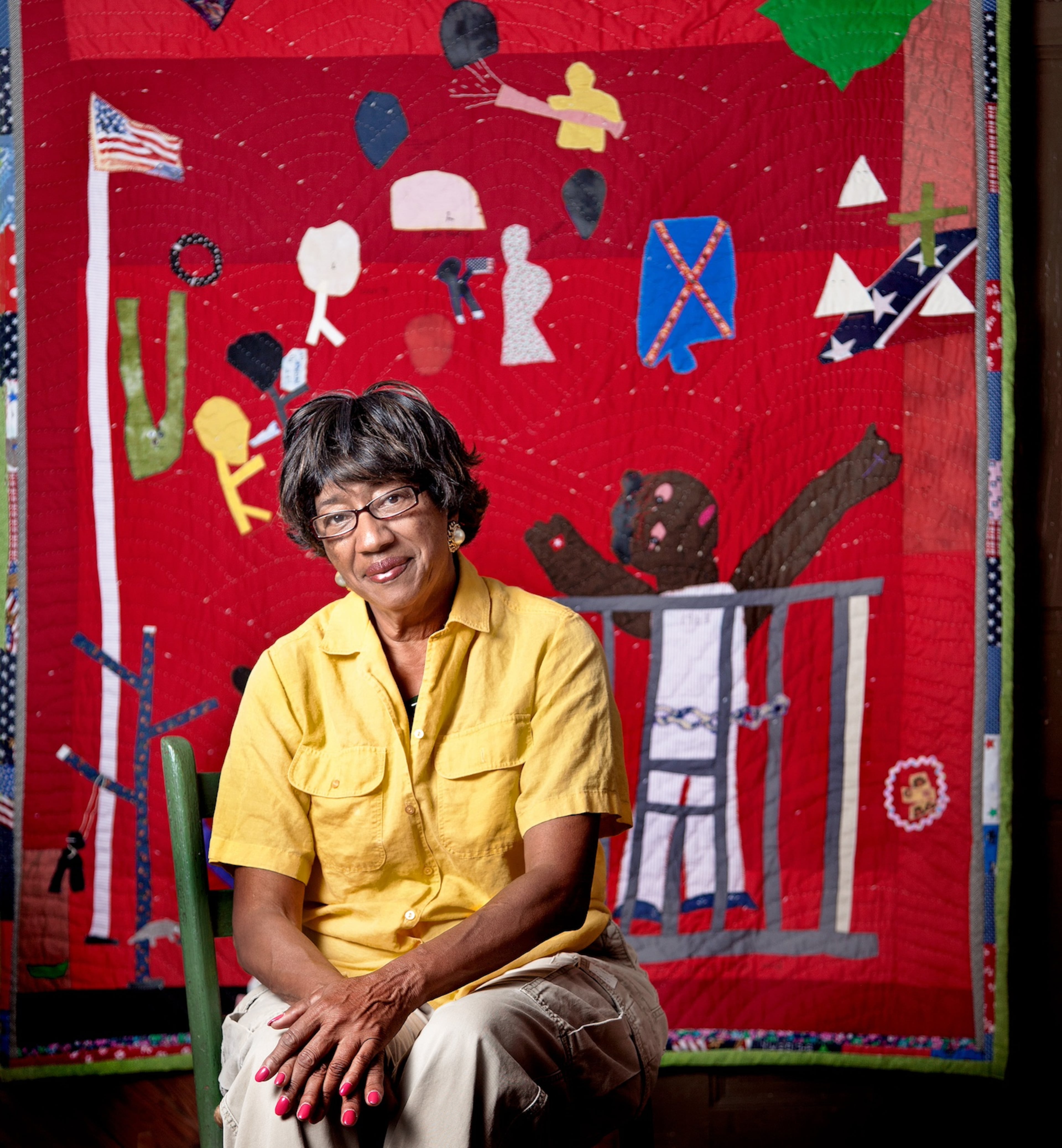 Alabama folk artist Yvonne Wells sits in front of one of her story quilts in this photograph by Jerry Siegel, which is now part of the permanent collection of the Smithsonian National Portrait Gallery. (Courtesy of Jerry Siegel)