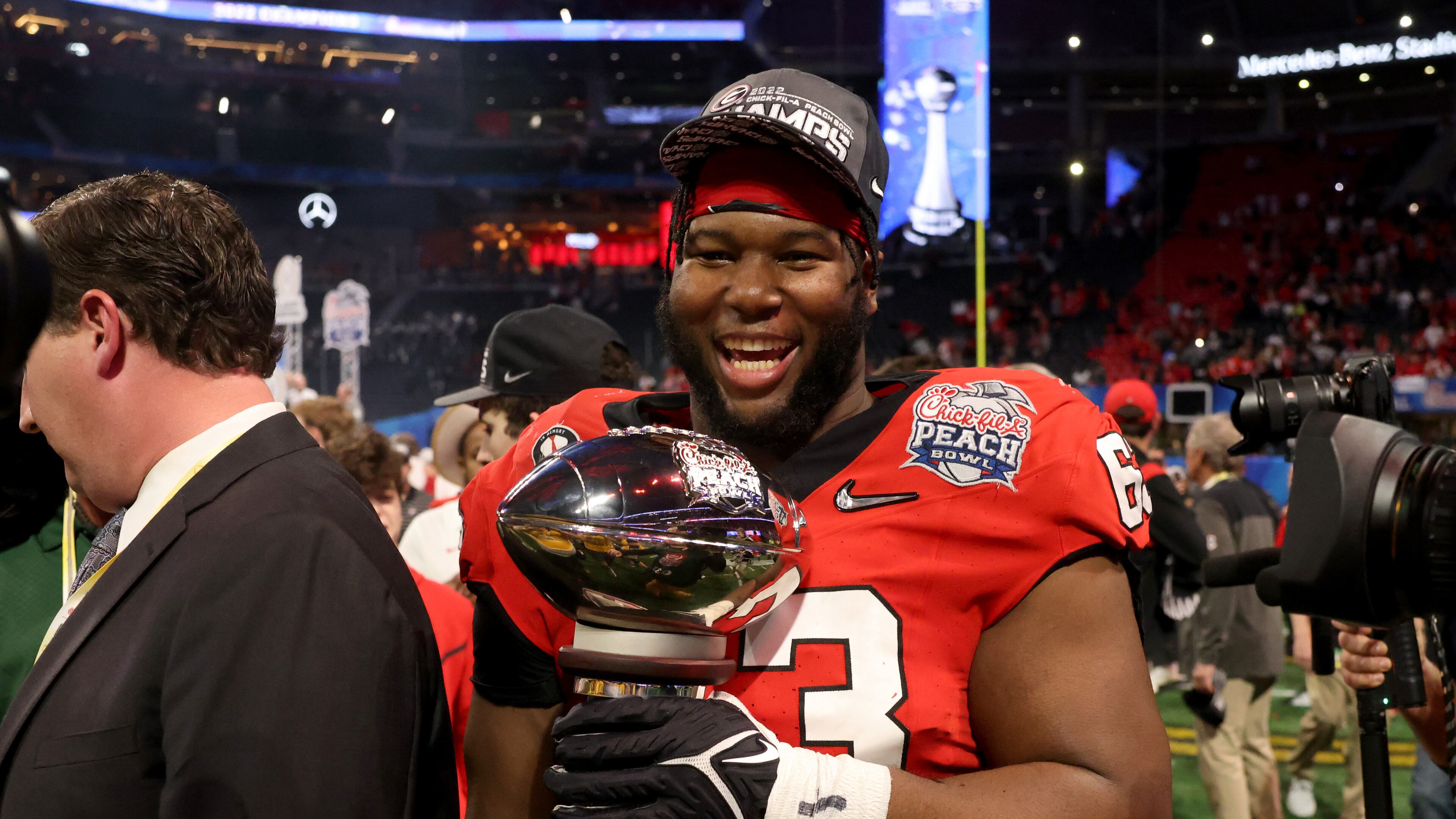 Georgia offensive lineman Sedrick Van Pran (63) carries the Peach Bowl trophy after their 42-41 win against Ohio State in the Peach Bowl Playoff Semifinal, at Mercedes-Benz Stadium, Sat., Dec. 31, 2022, in Atlanta. (Jason Getz / Jason.Getz@ajc.com)