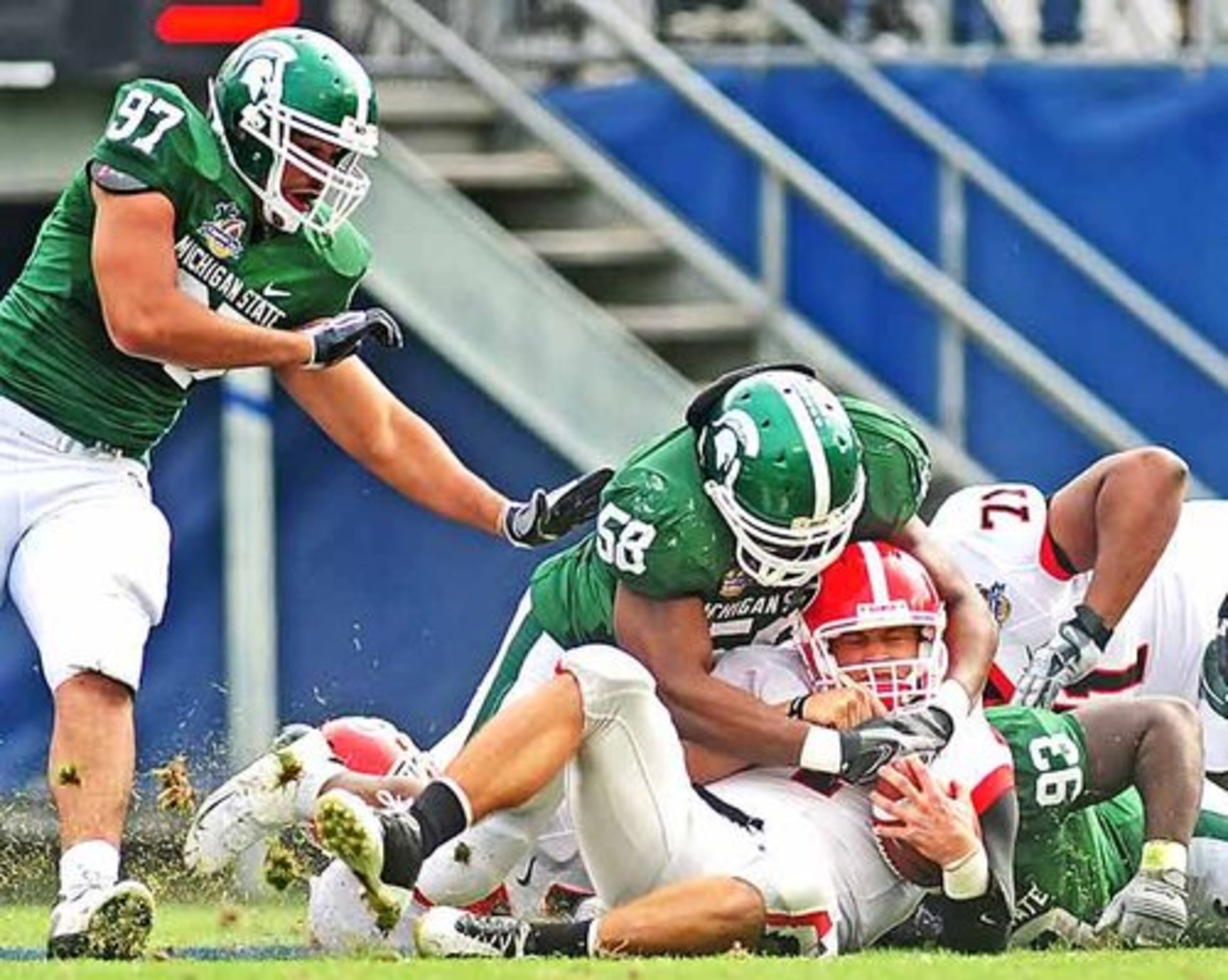 Georgia quarterback Matthew Stafford (7) is brought down by Michigan State defensive end Trevor Anderson (58) and Michigan State defensive tackle Antonio Jeremiah (93) during the second quarter. UGA started slow and was losing 6-3 at halftime, but scored in the 3rd quarter to go up 10-6.