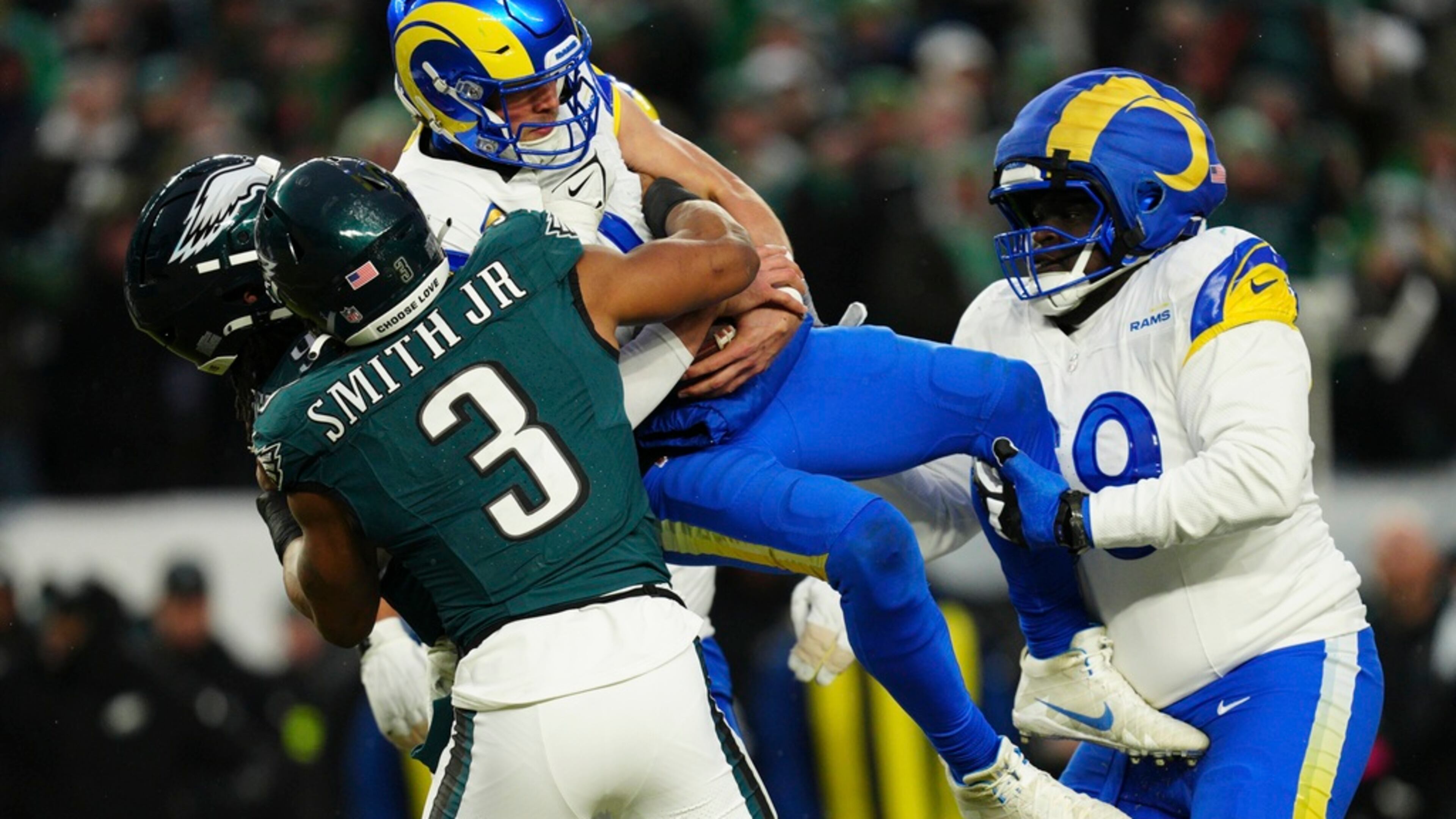 Los Angeles Rams quarterback and former Georgia star Matthew Stafford (9) is lifted as he's sacked by Philadelphia Eagles linebacker Nolan Smith Jr. (3) and Philadelphia Eagles defensive tackle Jalen Carter (98) during the first half of an NFL football NFC divisional playoff game Sunday, Jan. 19, 2025, in Philadelphia. (AP Photo/Derik Hamilton)