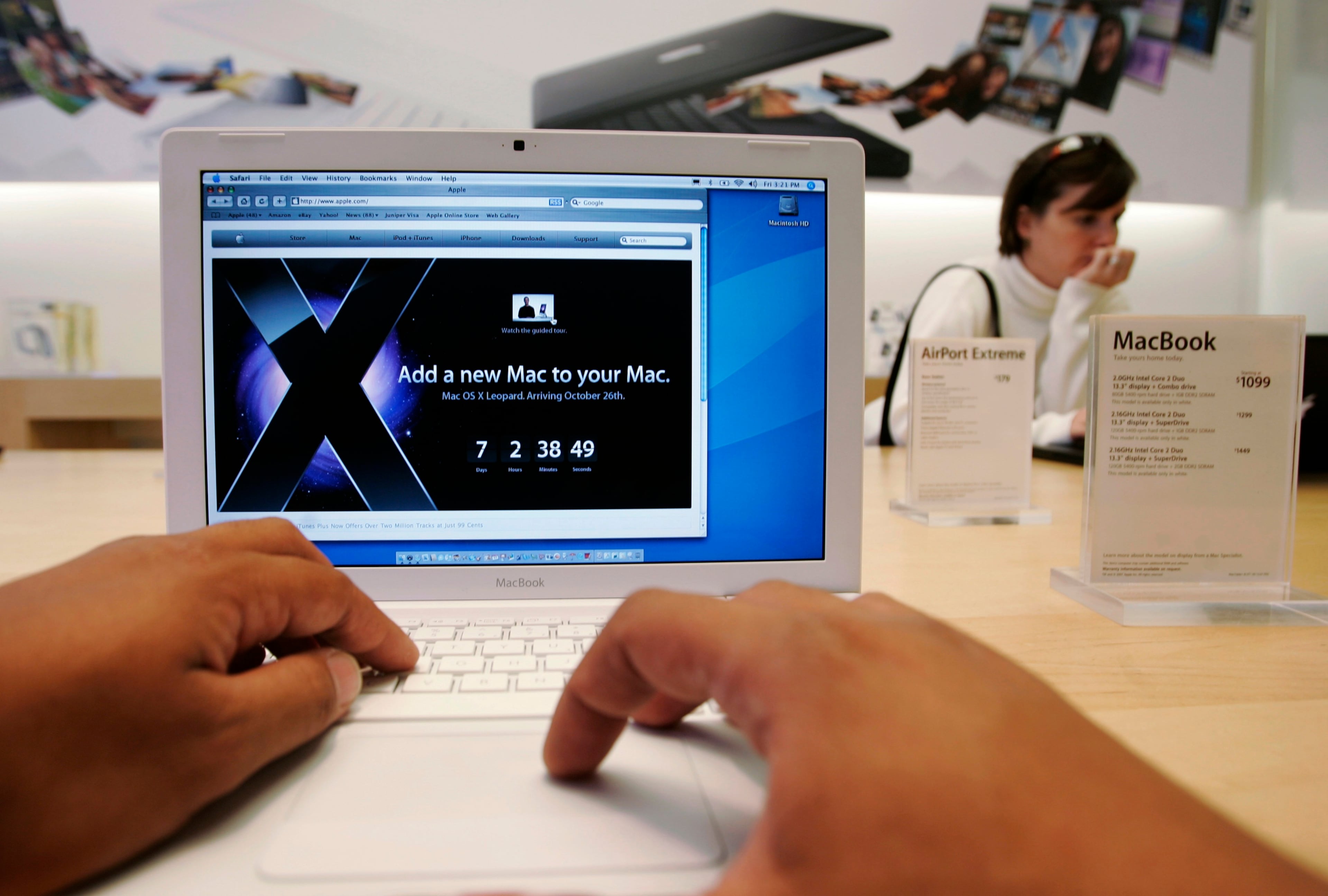 A customer uses an Apple MacBook with an advertisement for Leopard at an Apple store in Palo Alto, Calif., Friday, Oct. 19, 2007. (AP Photo/Paul Sakuma)