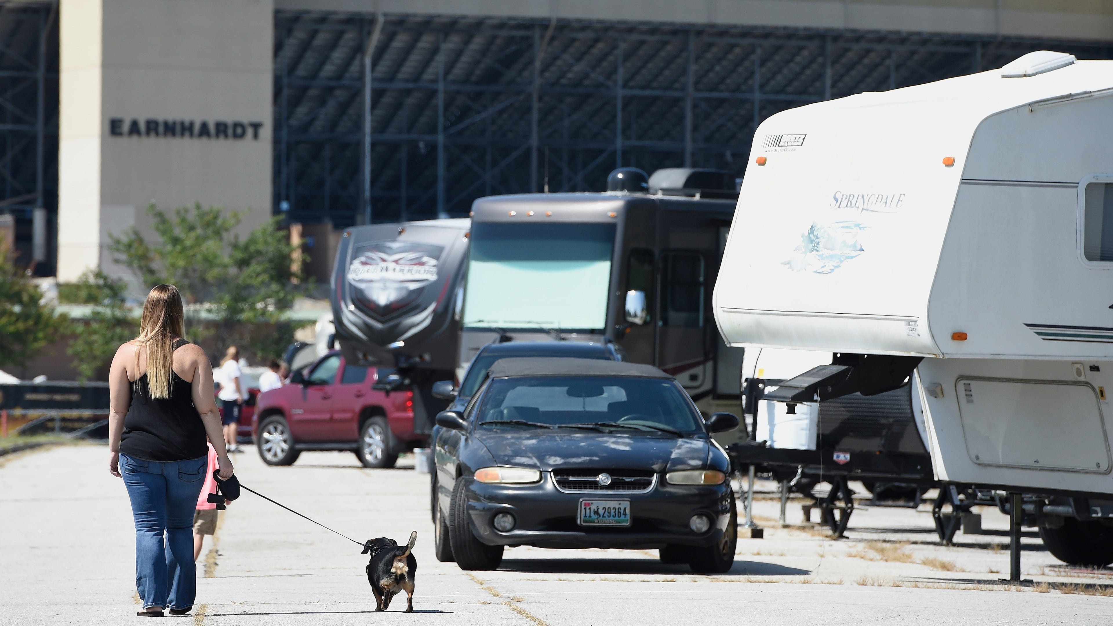 Chelsea Roberson, of Cape Coral, Fla., walks her dog near her parked RV at the Atlanta Motor Speedway, Friday, Sept. 8, 2017, in Hampton, Ga. Over 50 cameras and RV's are sheltering at the speedway from South Ga., South Carolina, and Florida. (AP Photo/Mike Stewart)