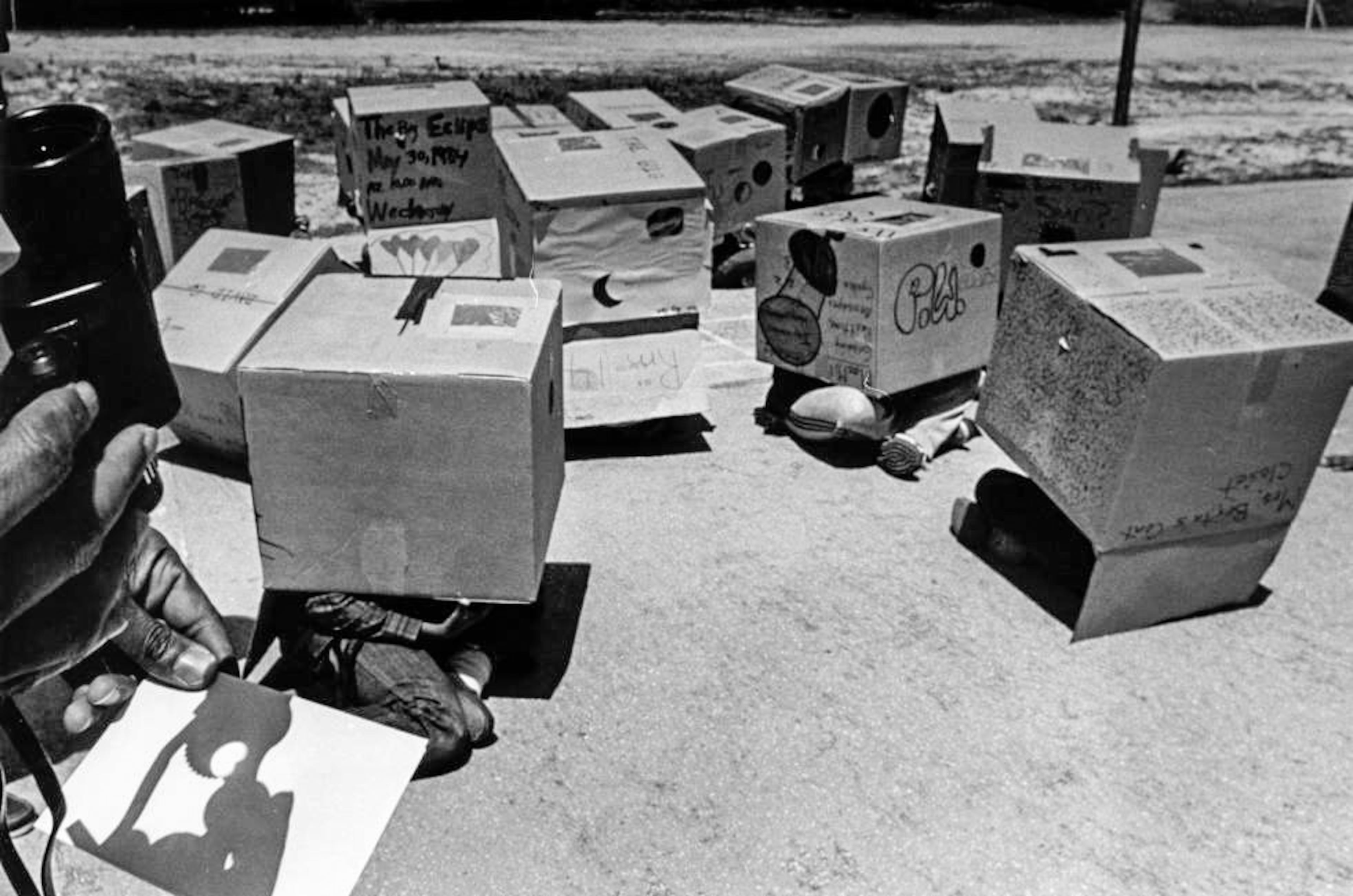On May 30, 1984, kids at Forrest Hills Elementary School in DeKalb Co. use boxes to view the eclipse. In the lower left corner of the photo, a card shows the sun in partial eclipse. This is what the kids are viewing inside of their boxes.