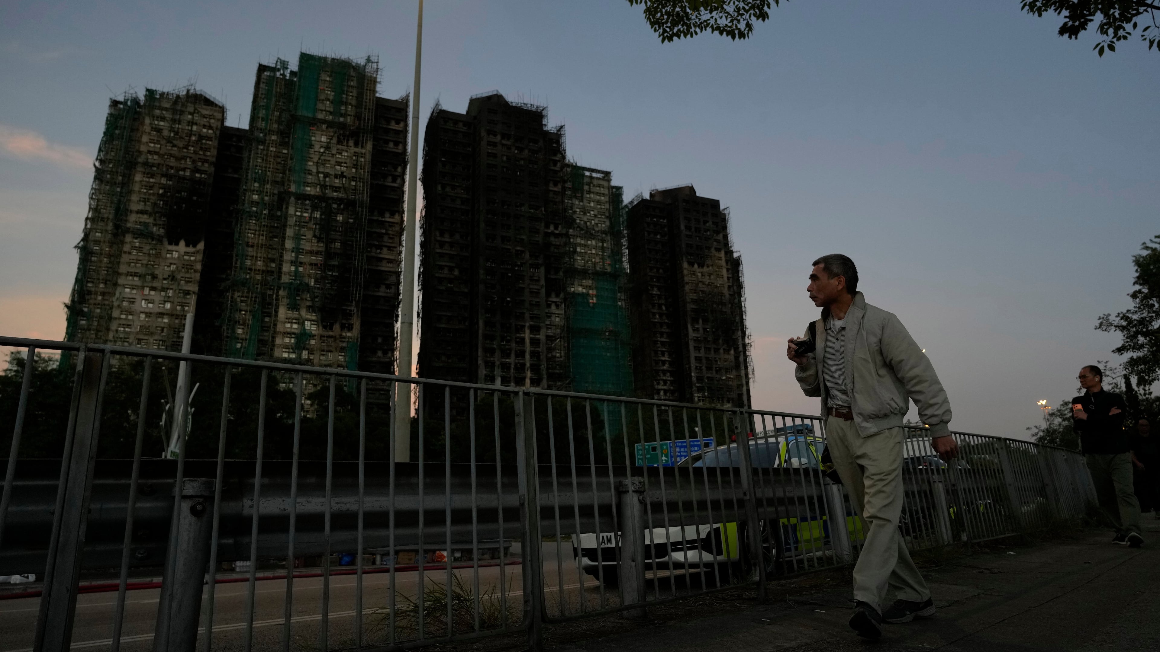 A man walks past the burnt buildings after a deadly fire that started Wednesday at Wang Fuk Court, a residential estate in the Tai Po district of Hong Kong's New Territories, Friday, Nov. 28 2025. (AP Photo/Ng Han Guan)
