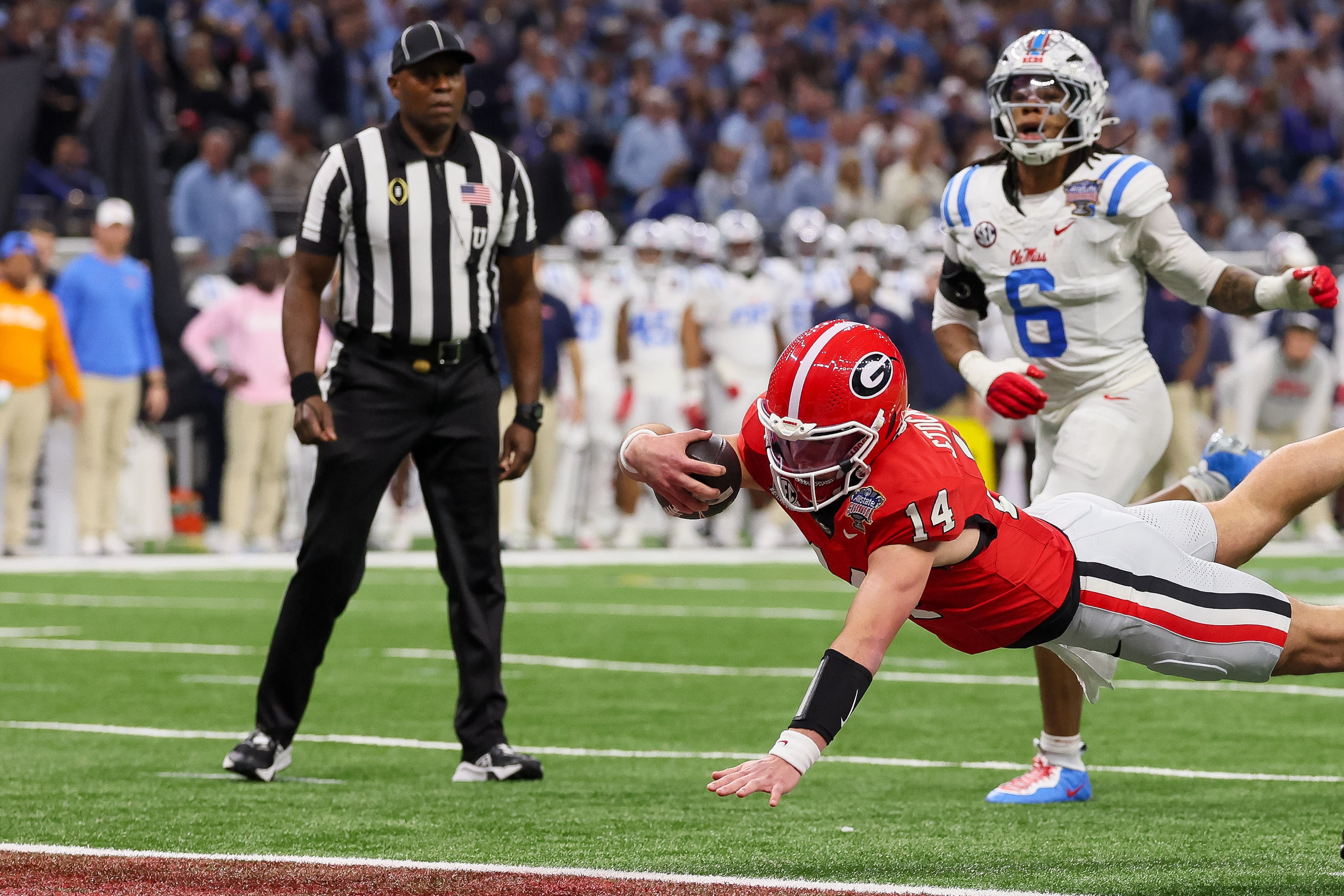 Georgia Bulldogs quarterback Gunner Stockton (14) dives into the end zone for a 12 yard touchdown run against the Ole Miss Rebels during the second quarter of the NCAA College Football Playoff quarterfinal game at the Sugar Bowl in the Caesars Superdome, Thursday, Jan. 1, 2026, in New Orleans. (Jason Getz/AJC)