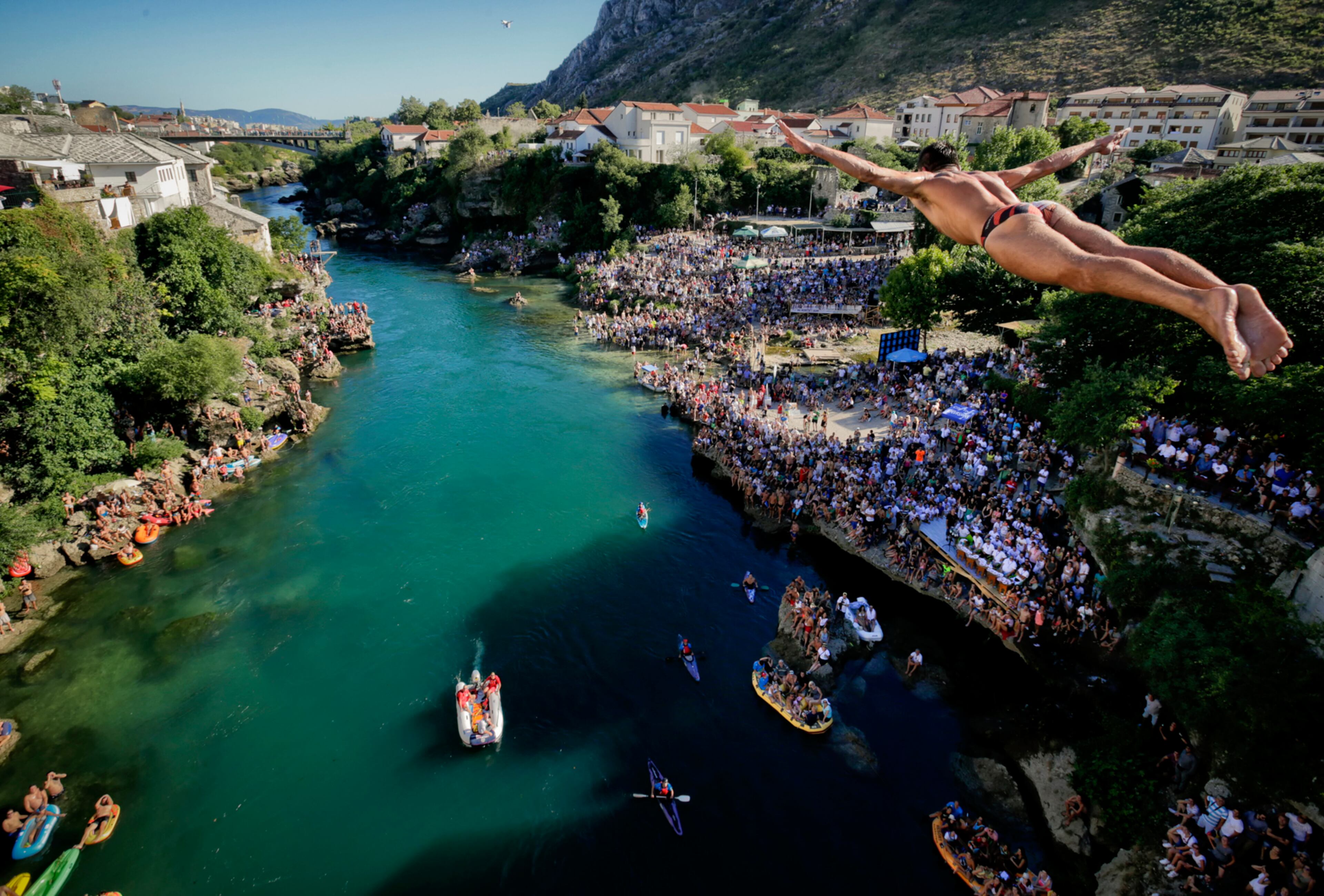 In this photograph taken on Sunday, July 30, 2017, a man dives from the Old Bridge in Mostar, Bosnia, during an annual diving competition that has been drawing crowds for more than 4.5 centuries. More than 10,000 spectators converged on the southern Bosnian city at the weekend to watch 41 daring men take a jump from the 27-meter-high historic Old Bridge into the cold, fast-flowing Neretva River below, as part of the Mostar's 451st annual diving competition.(AP Photo/Amel Emric)