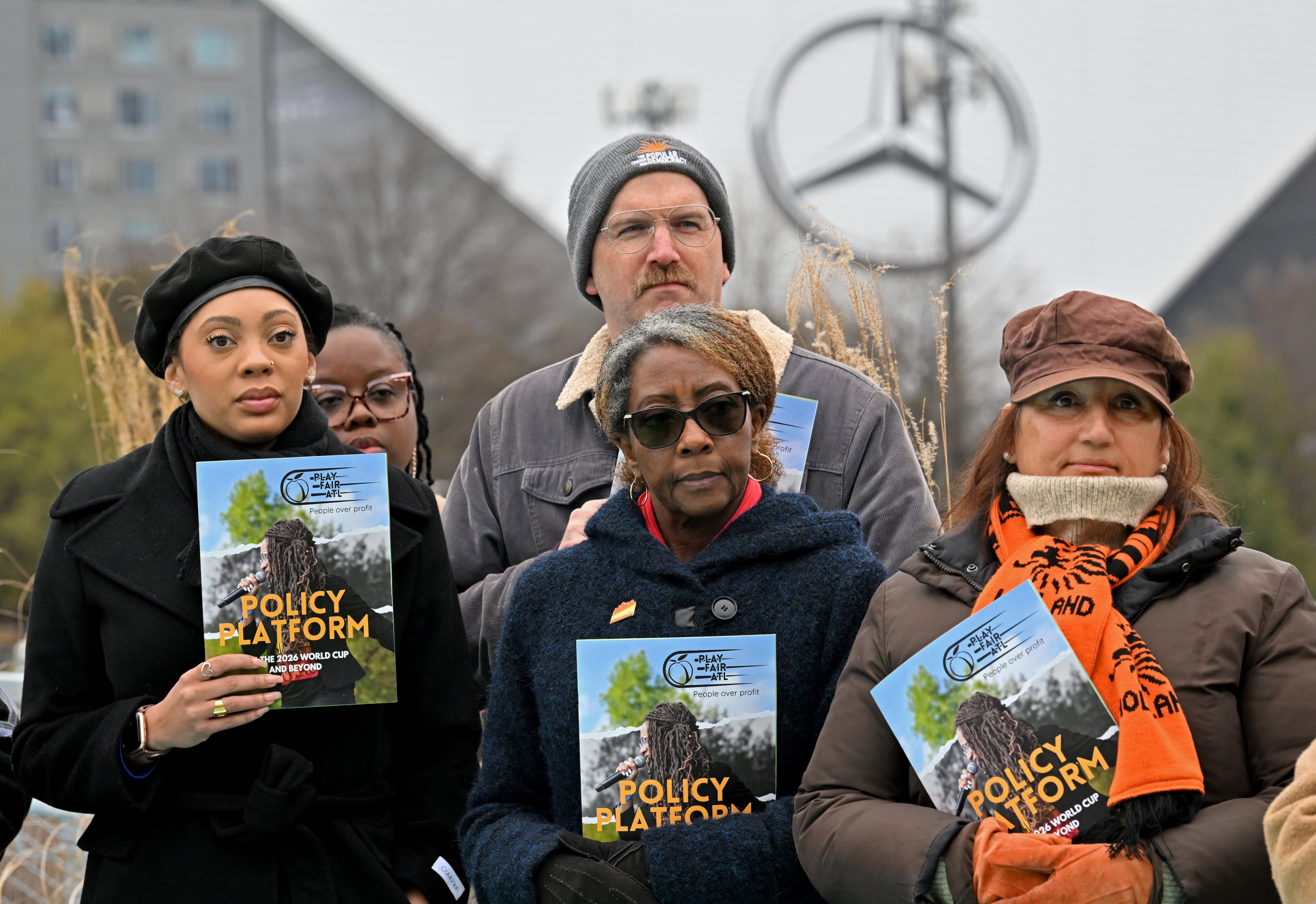 Supporters hold pamphlets during an event to launch its policy platform outlining community-driven demands ahead of the 2026 FIFA World Cup on the Steele Bridge near the Mercedes-Benz Stadium, Thursday, December 4, 2025, in Atlanta. (Hyosub Shin / AJC)