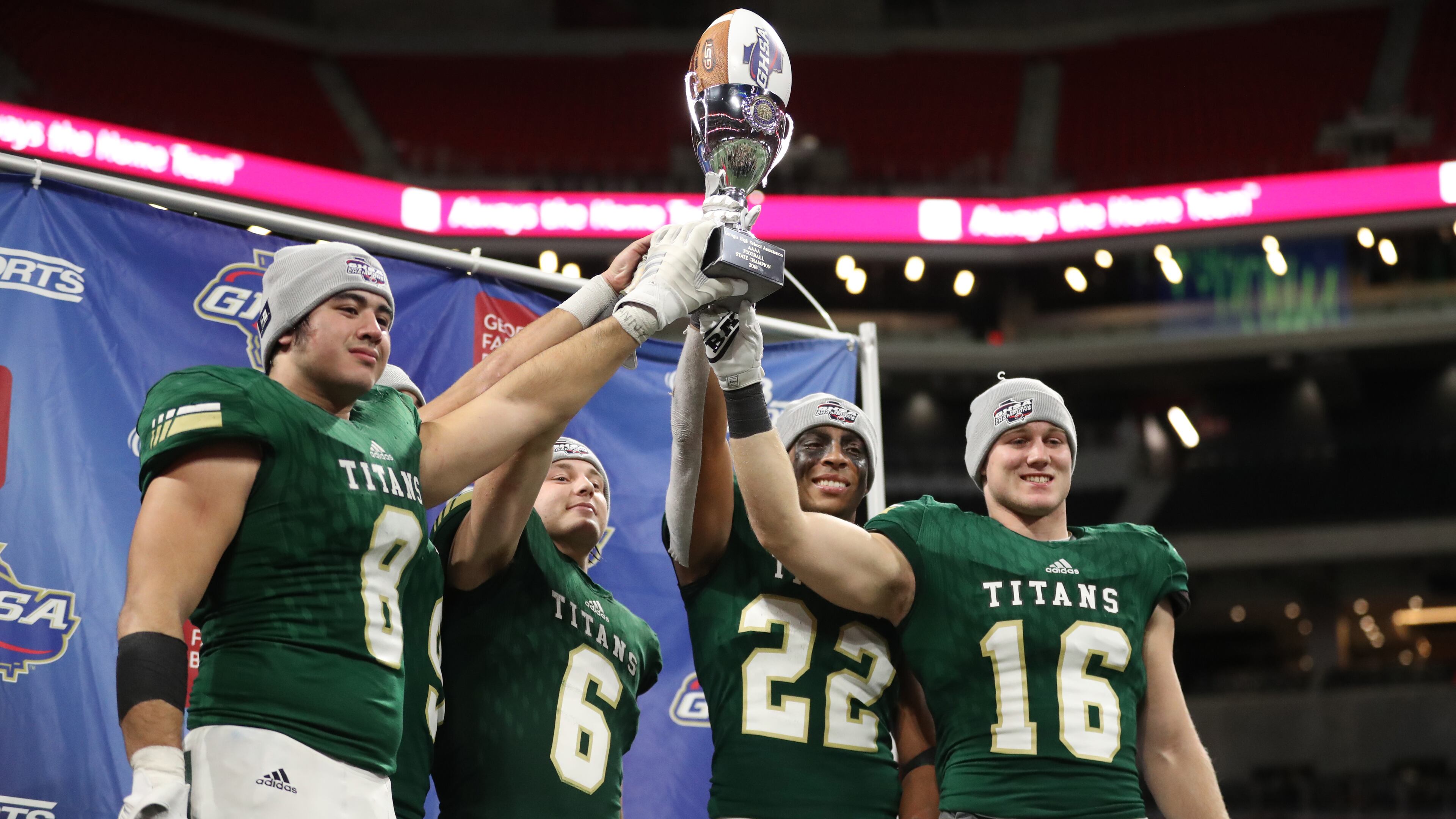 Class AAAA champions: Blessed Trinity players (from left) Jr Bivens (8), Ryan Davis (6), Steele Chambers (22), and JD Bertrand (16) celebrate with the state championship trophy after their 23-9 win against Cartersville at Mercedes-Benz Stadium Wednesday, December 12, 2018, in Atlanta. (Jason Getz/Special)
