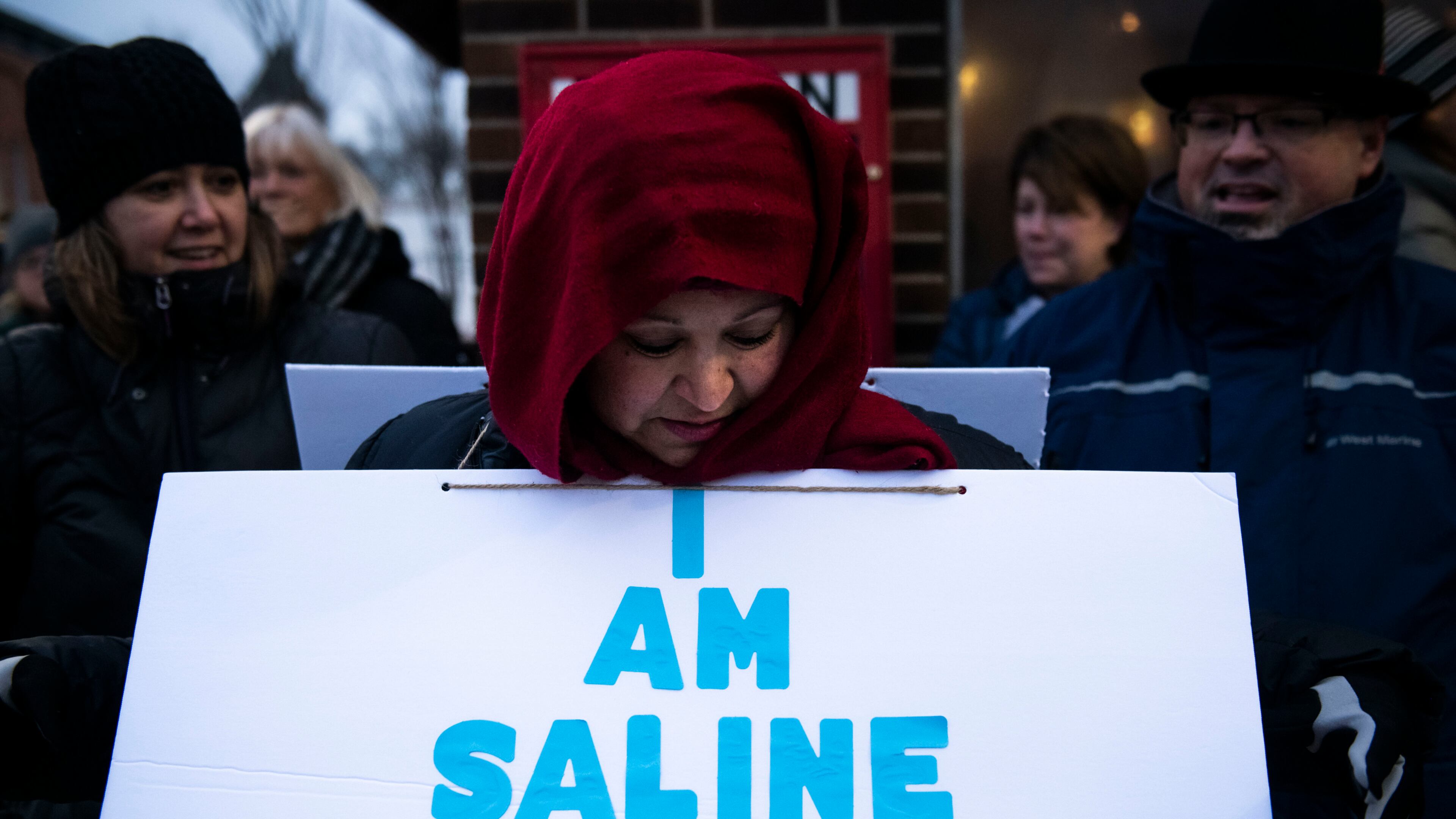 Valerie Casarez Helmer looks down at her sign before marching during the Saline Diversity Inclusion Rally.
