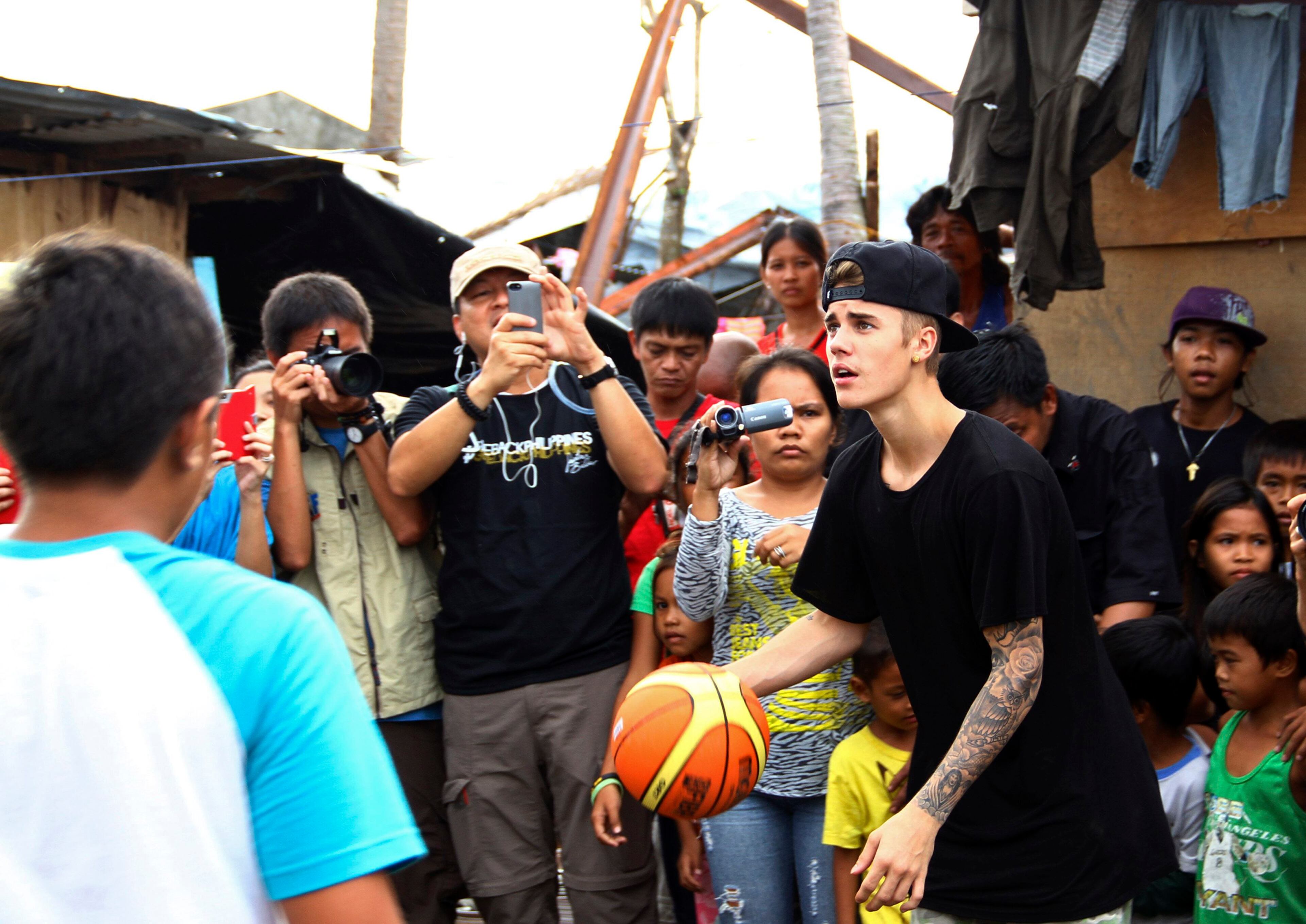 Pop singer Justin Bieber plays basketball during his visit to an evacuation centre at San Jose town, Tacloban city, central Philippines December 10, 2013. Bieber flew unannounced to Tacloban city on Tuesday to visit survivors a month after Typhoon Haiyan battered central Philippines, local media reported. REUTERS/Dennis Jay Santos