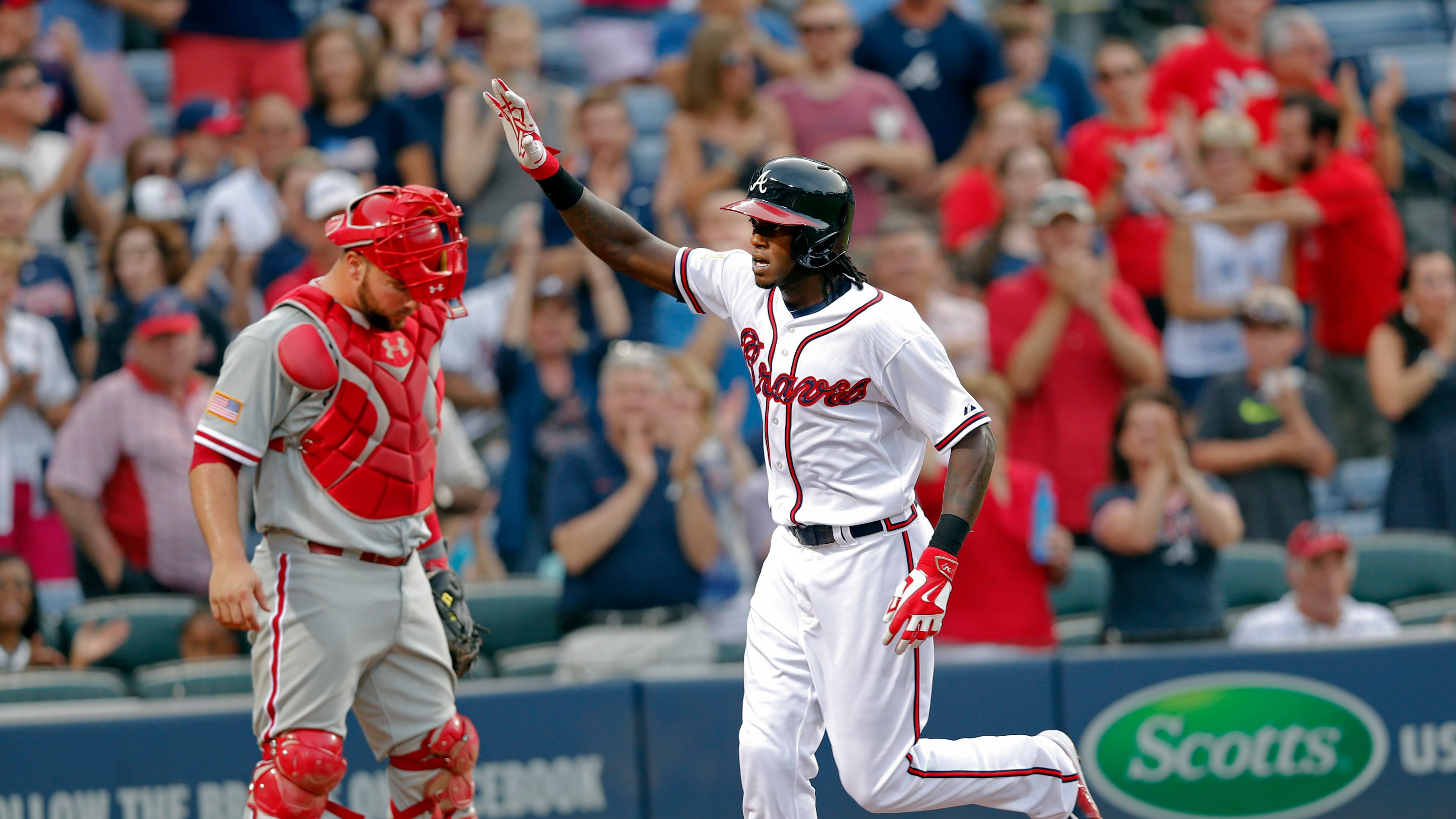 Atlanta Braves' Cameron Maybin, right, gestures as he runs past Philadelphia Phillies catcher Cameron Rupp to score after hitting a solo home run in the second inning of a baseball game Saturday, July 4, 2015, in Atlanta. (AP Photo/John Bazemore)