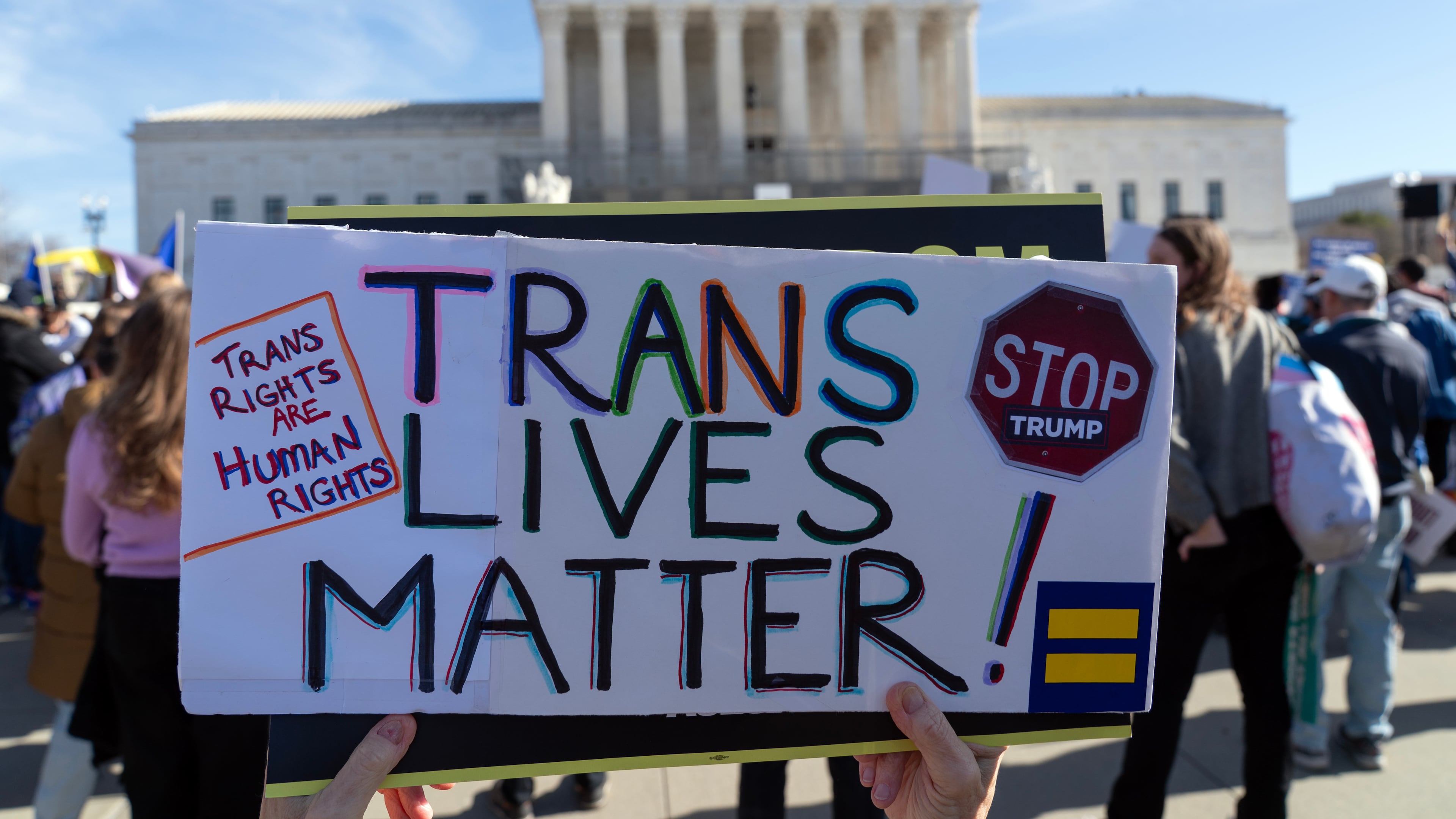 Protesters gather outside the Supreme Court as it hears arguments over state laws barring transgender girls and women from playing on school athletic teams, Tuesday, Jan. 13, 2026, in Washington. (AP Photo/Jose Luis Magana)