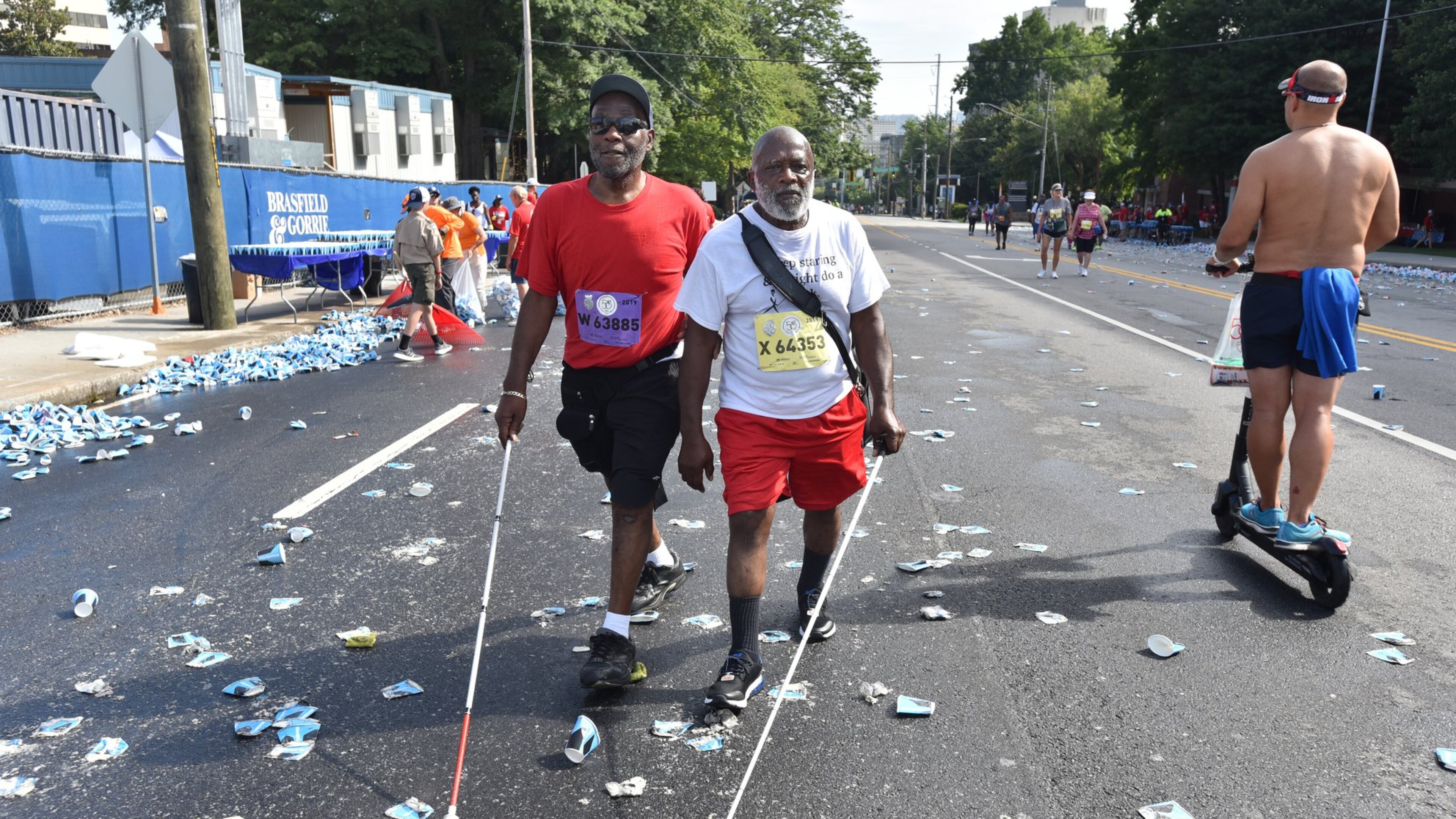 Willard Walker (left) and his brother John W. Smith, both legally blind, were among the last group of walkers and runners to make their way down Peachtree Road during the 50th AJC Peachtree Road Race on the Fourth of July. (Photo: Hyosub Shin / Hyosub.Shin@ajc.com)