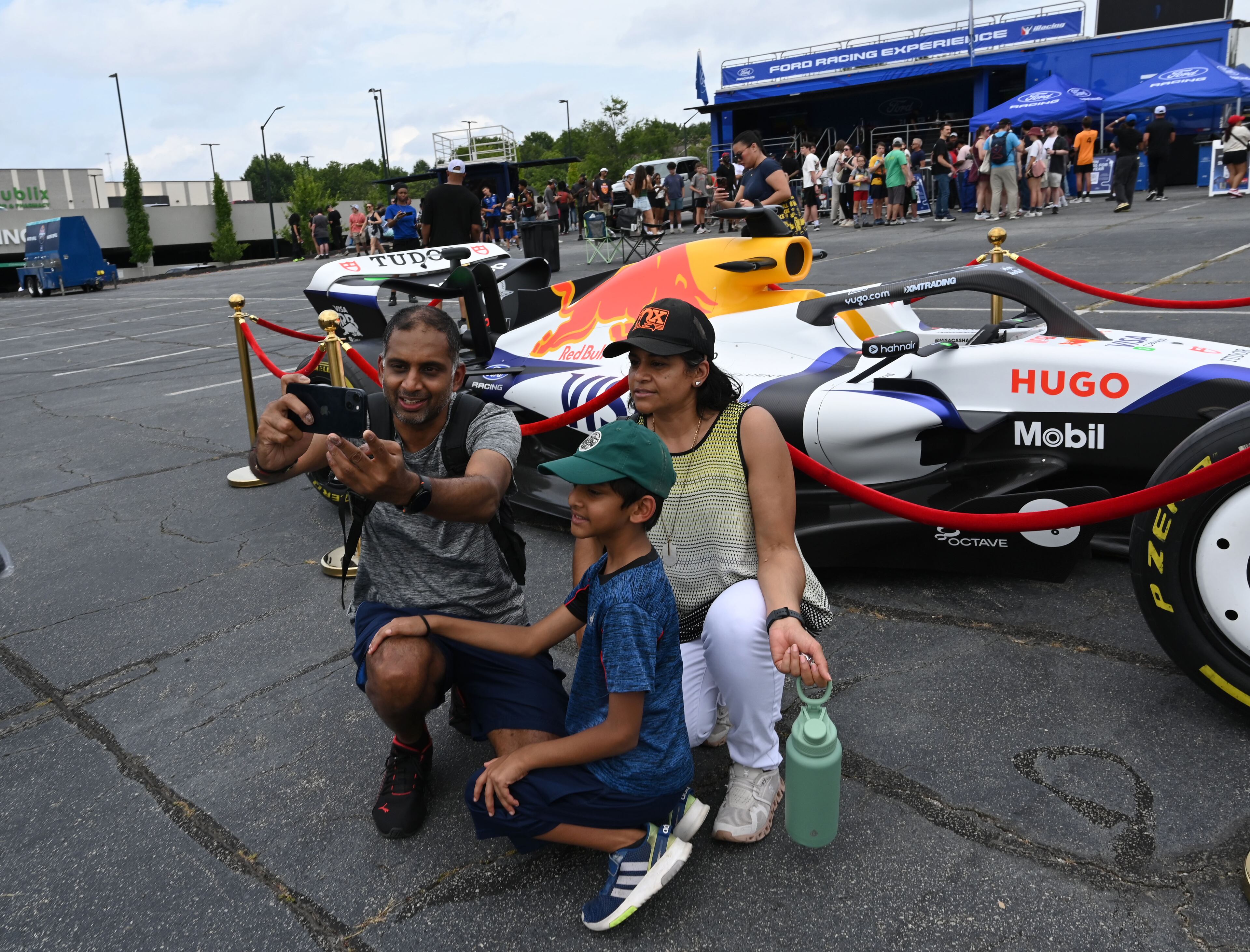 Remal, left, and Harsha Patel and their son Rahil, 8, take a selfie in front of HUGO Formula 1 racing car during Red Bull Showrun Atlanta Presented By Ford Racing on Saturday, August 1, 2026, in Atlanta. Atlanta city officials this week approved permits for the Red Bull Showrun that will allow the live motorsports demonstration event to go on as advertised along a roughly half-mile stretch of Hank Aaron Drive — a backup location after earlier plans to hold the event near Piedmont Park ran into opposition from Midtown residents. (Hyosub Shin/AJC)
