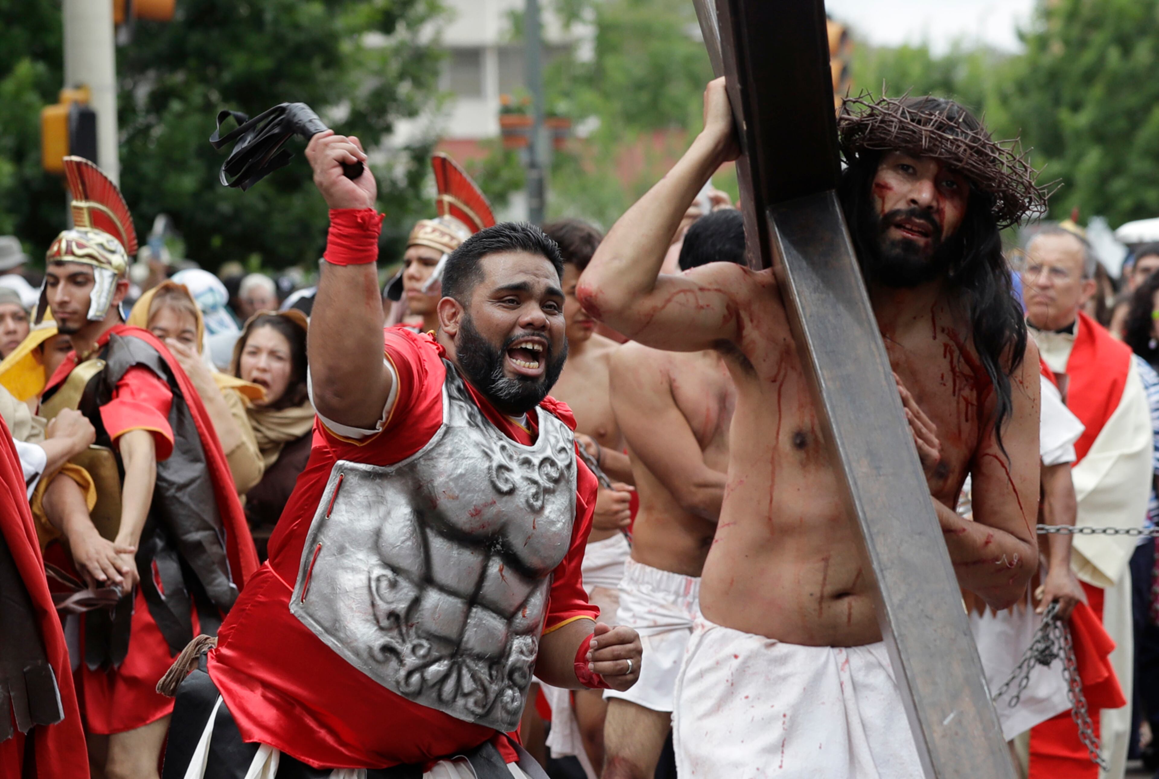 Luis Amaro, right, playing the part of Jesus, is hit by whips as he carries a cross through downtown San Antonio during a re-enactment of the Passion of Christ, Friday, April 14, 2017. (AP Photo/Eric Gay)