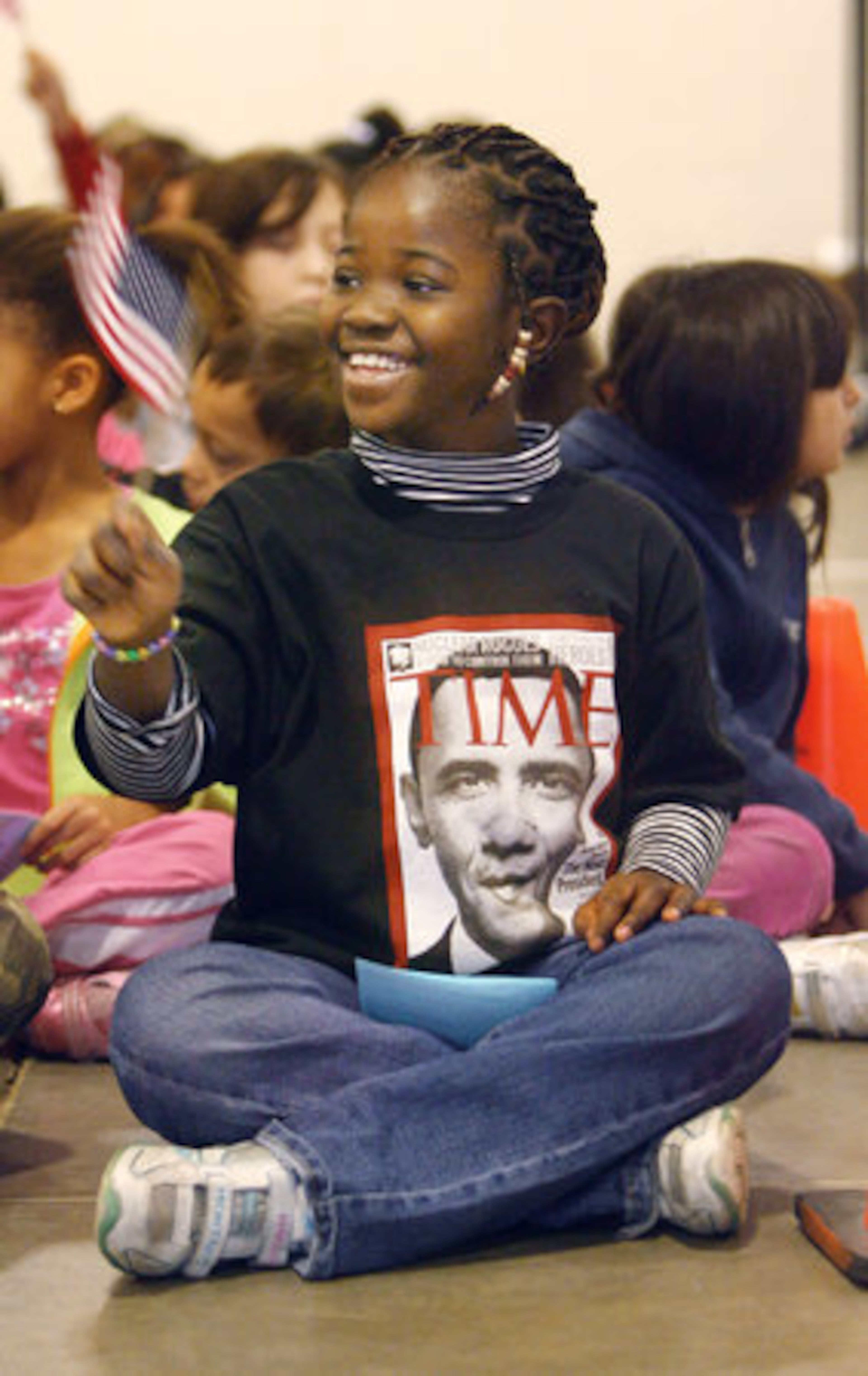 Lois Osei, a second grade student, wears a Barack Obama T-shirt of a Time Magazine cover purchased for her by her father as she waves the American flag as students at Chesney Elementary School in Duluth staged their own presidential swearing-in ceremony.