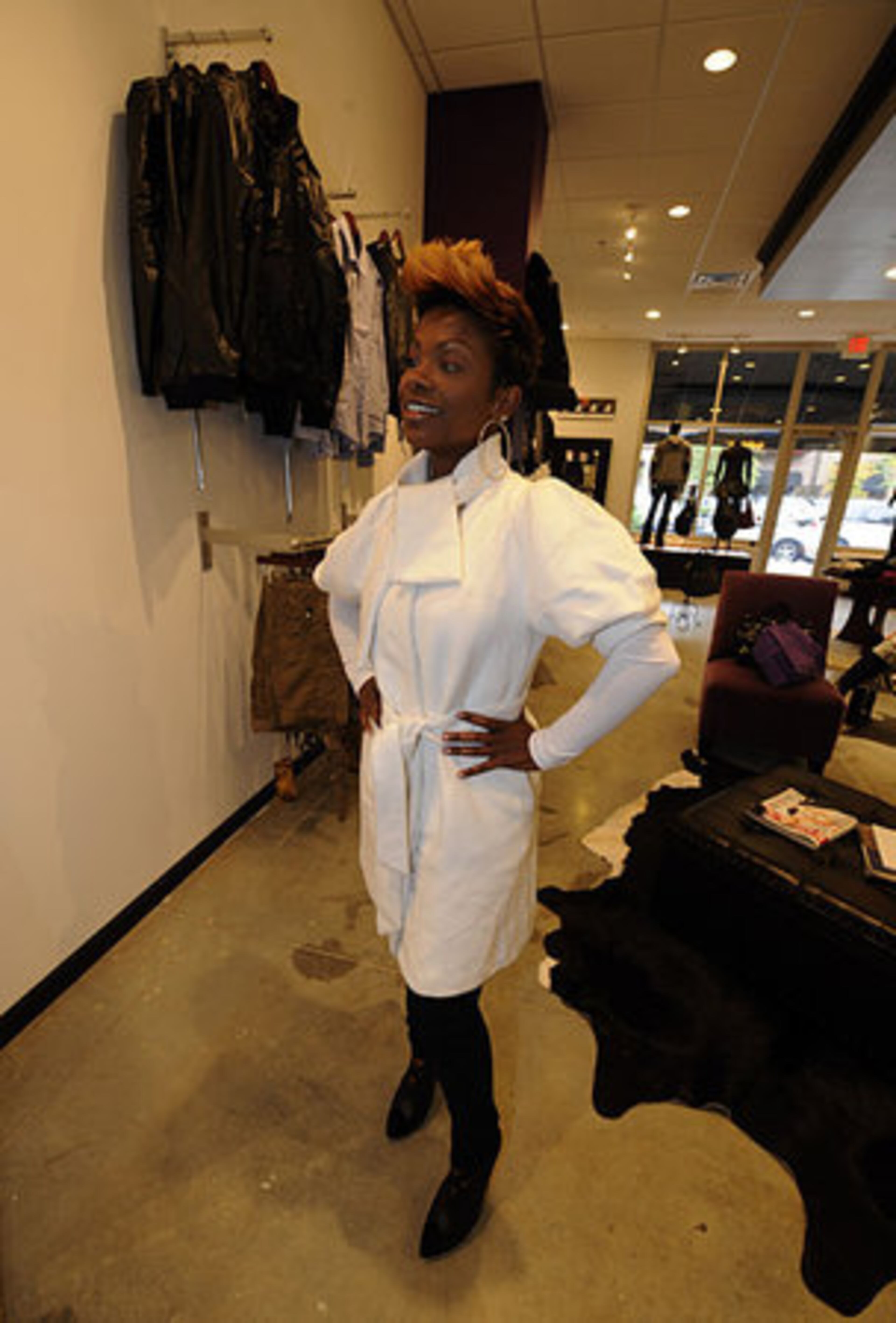 Kandi Burruss tries on a coat inside Tags, her new boutique.