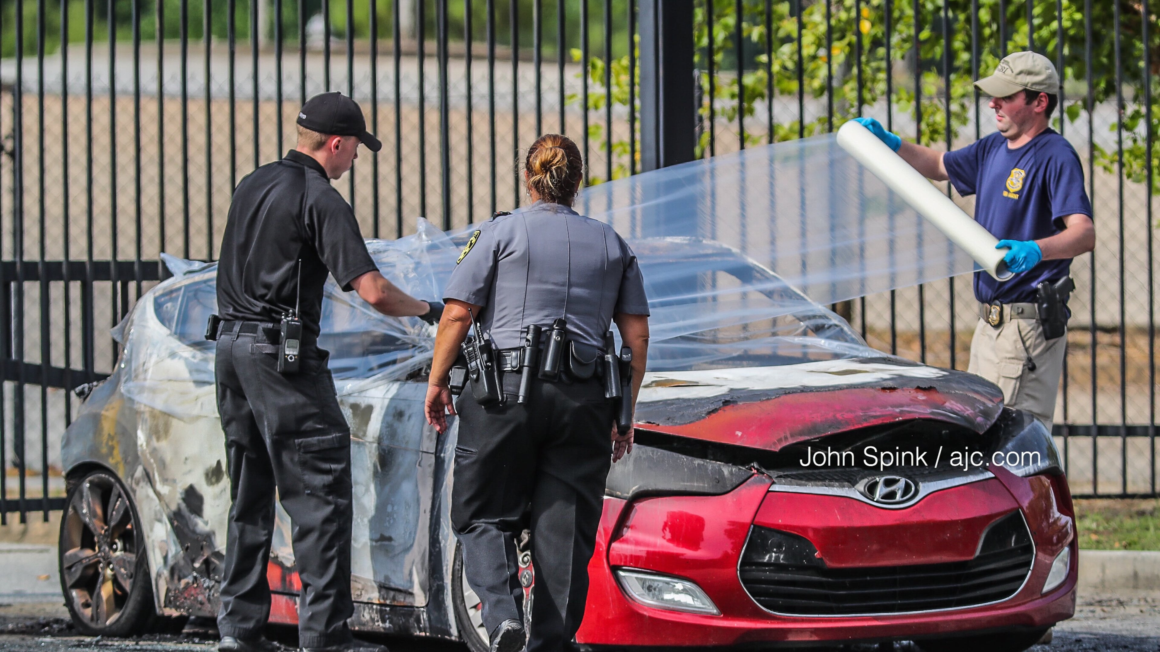 Authorities wrap up a burned car for transport to the GBI. A body was found inside the car, South Fulton police said.
