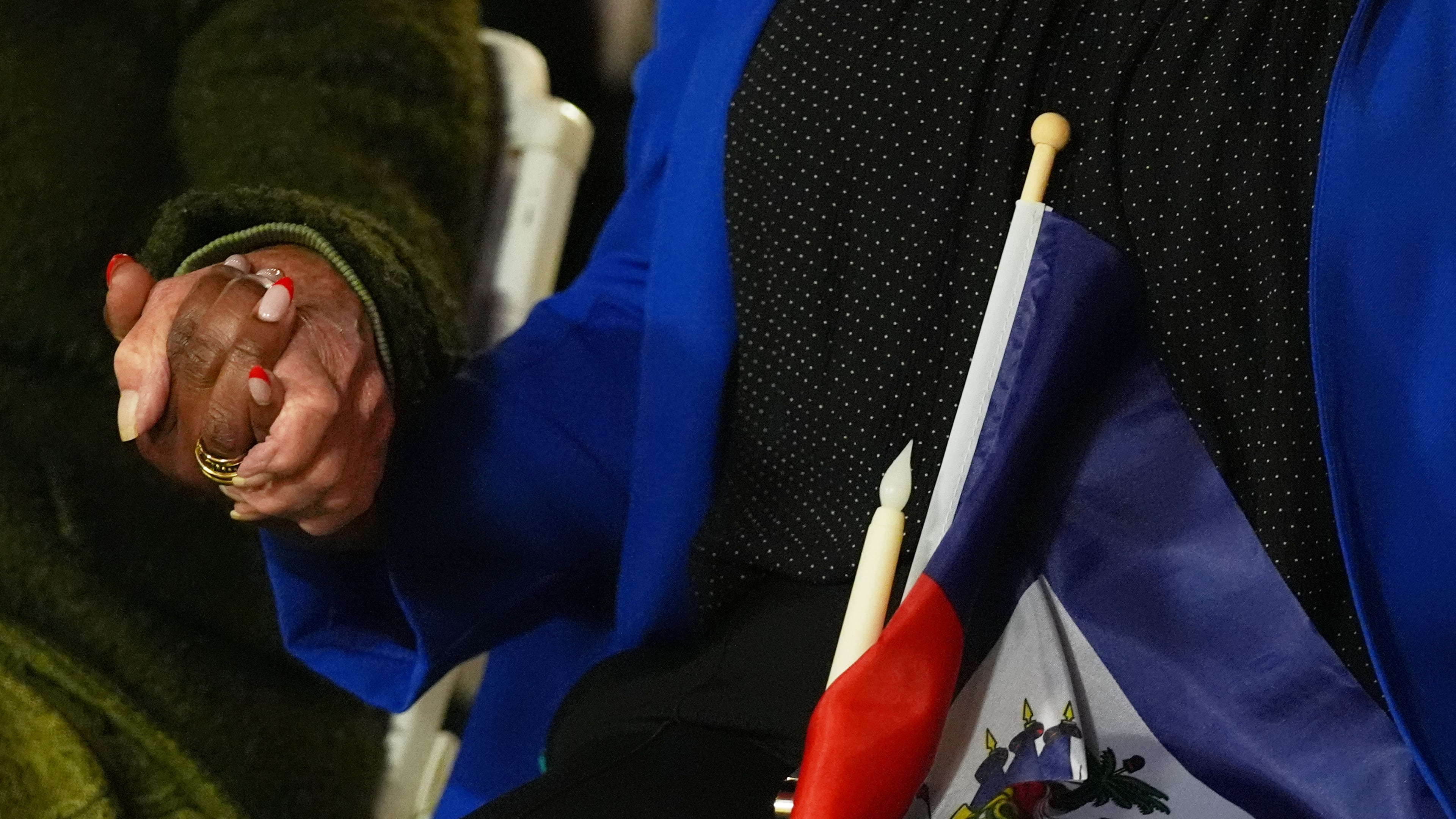 FILE - People hold hands and a Haitian flag during a vigil at the Little Haiti Cultural Complex after a federal judge blocked the Trump administration from ending temporary immigration status, or TPS, for Haitians, Feb. 3, 2026, in North Miami. (AP Photo/Lynne Sladky, File)