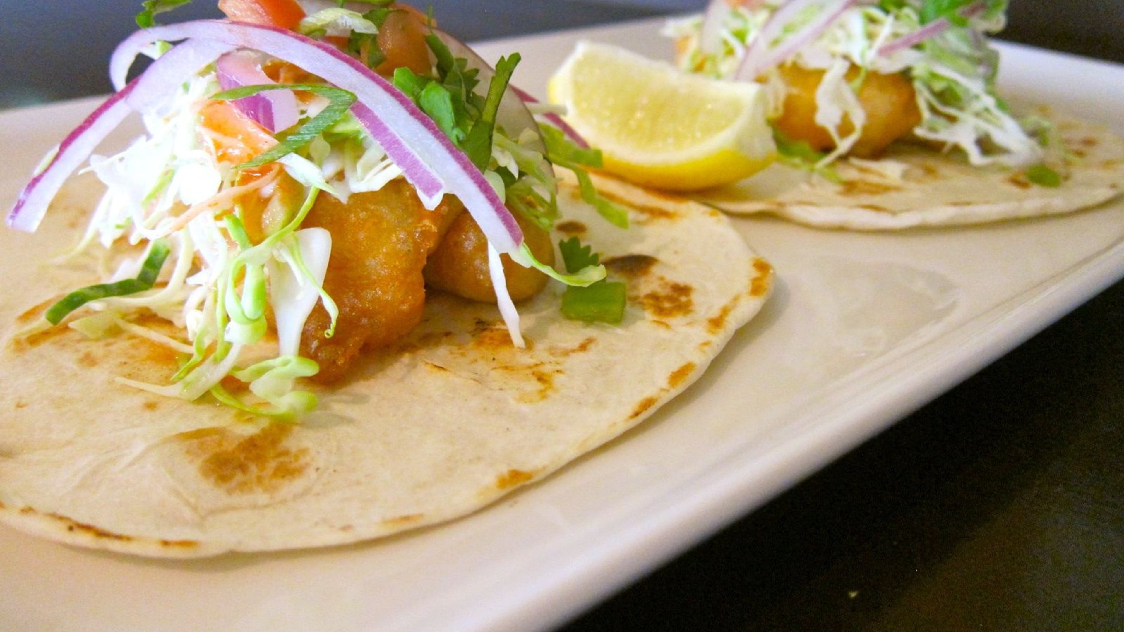 Harp-battered fish tacos with a spicy red chili aioli, fresh cabbage, green onion, tomato pico and cilantro. Contributed by Fado Irish Pub