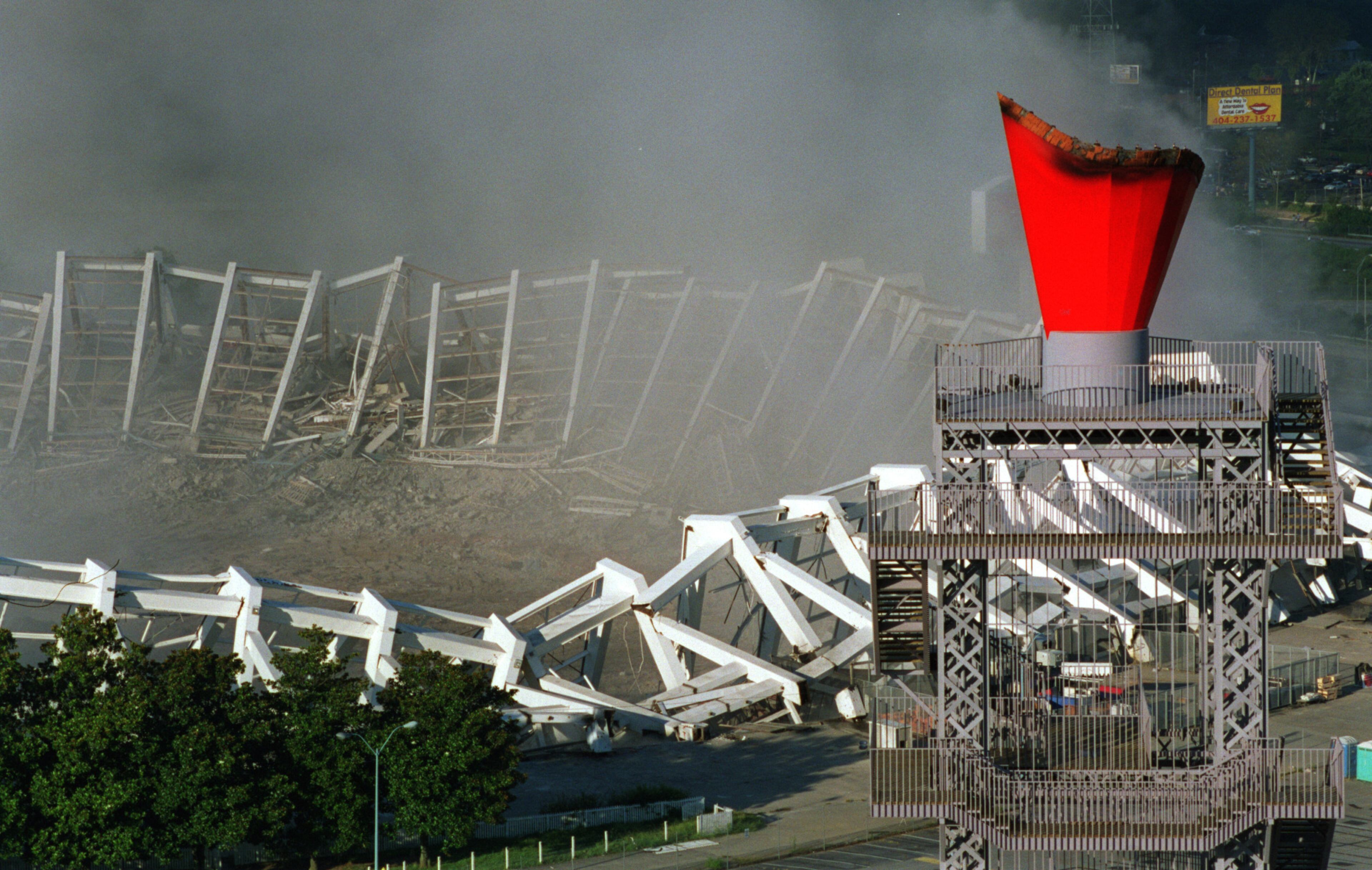 970802 ATLANTA: The transplanted Olympic Caldron, right, rises up above the remains of Atlanta Fulton County Stadium after the implosion as the dust cloud begins to dissipate. Demolition crews imploded it down with a series of 1,200 successive detonations. The space will be turned into 4,000 parking spaces. (AJC Staff Photo/Kevin Keister) 8/97