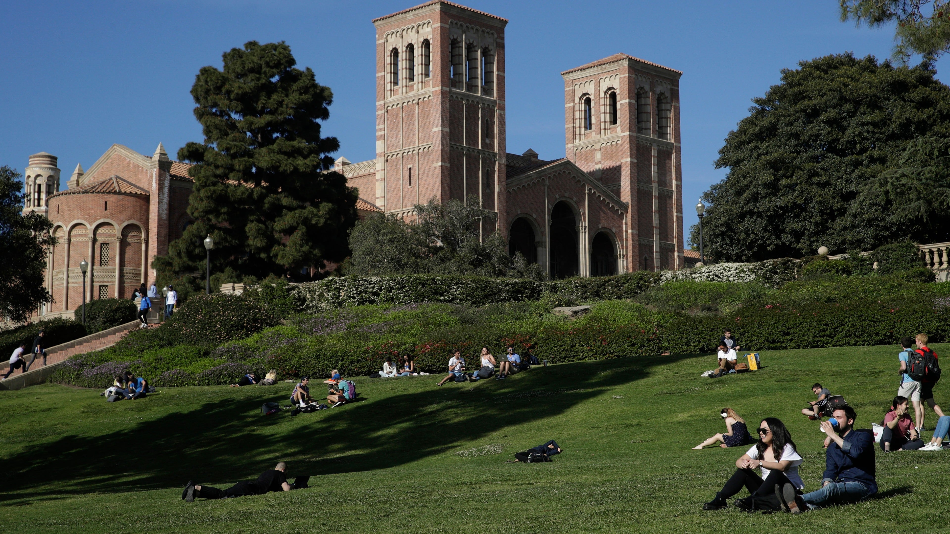 FILE - Students sit on the lawn near Royce Hall at UCLA in the Westwood section of Los Angeles on April 25, 2019. (AP Photo/Jae C. Hong, File)