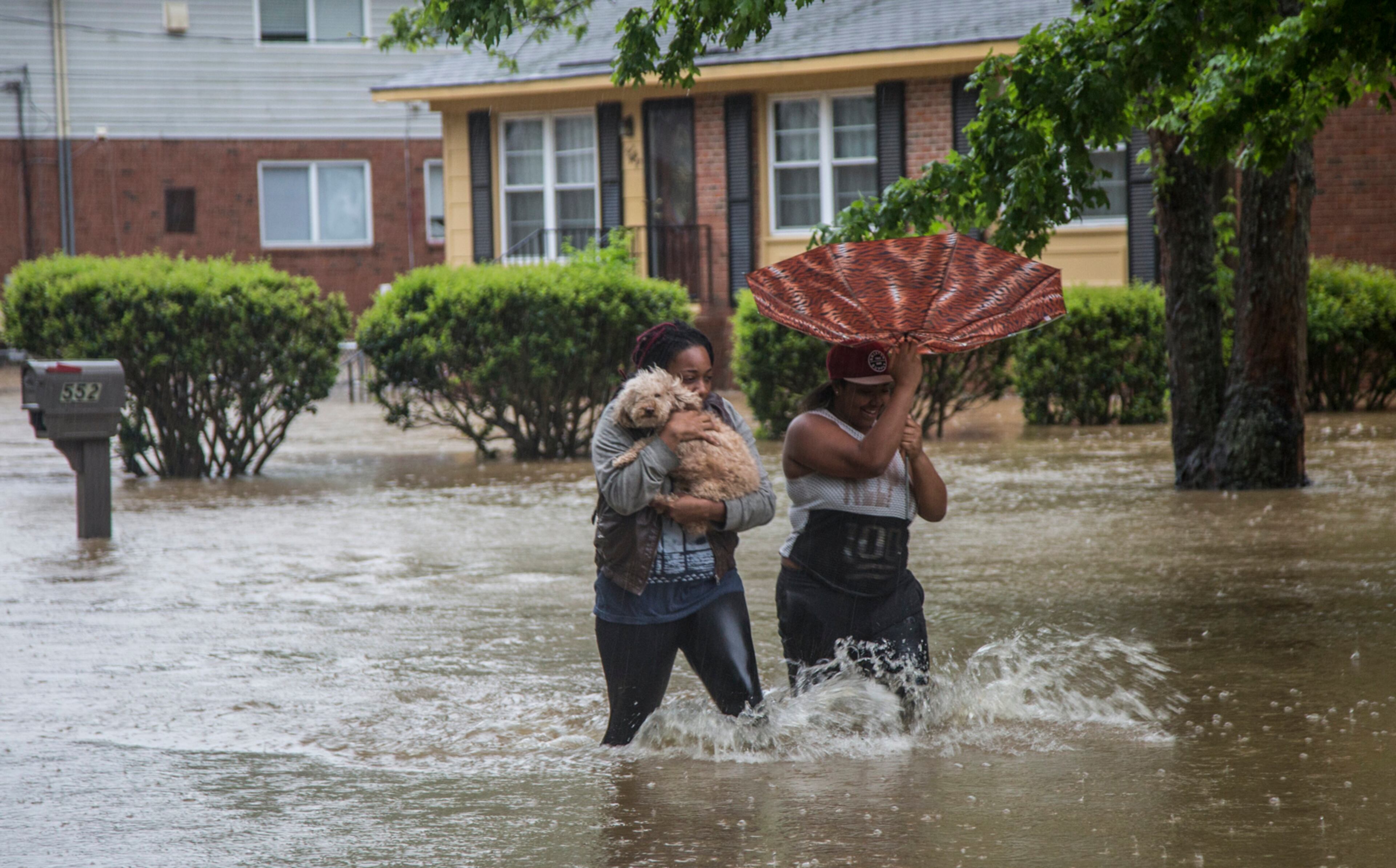 Nautical Jackson, left, and Aniya Ruffin walk through floodwaters with their dog, Chestnut, as water threatens to enter their home on Dacian Road in Raleigh, N.C., on Tuesday, April 25, 2017. (Travis Long/Raleigh News & Observer/TNS)