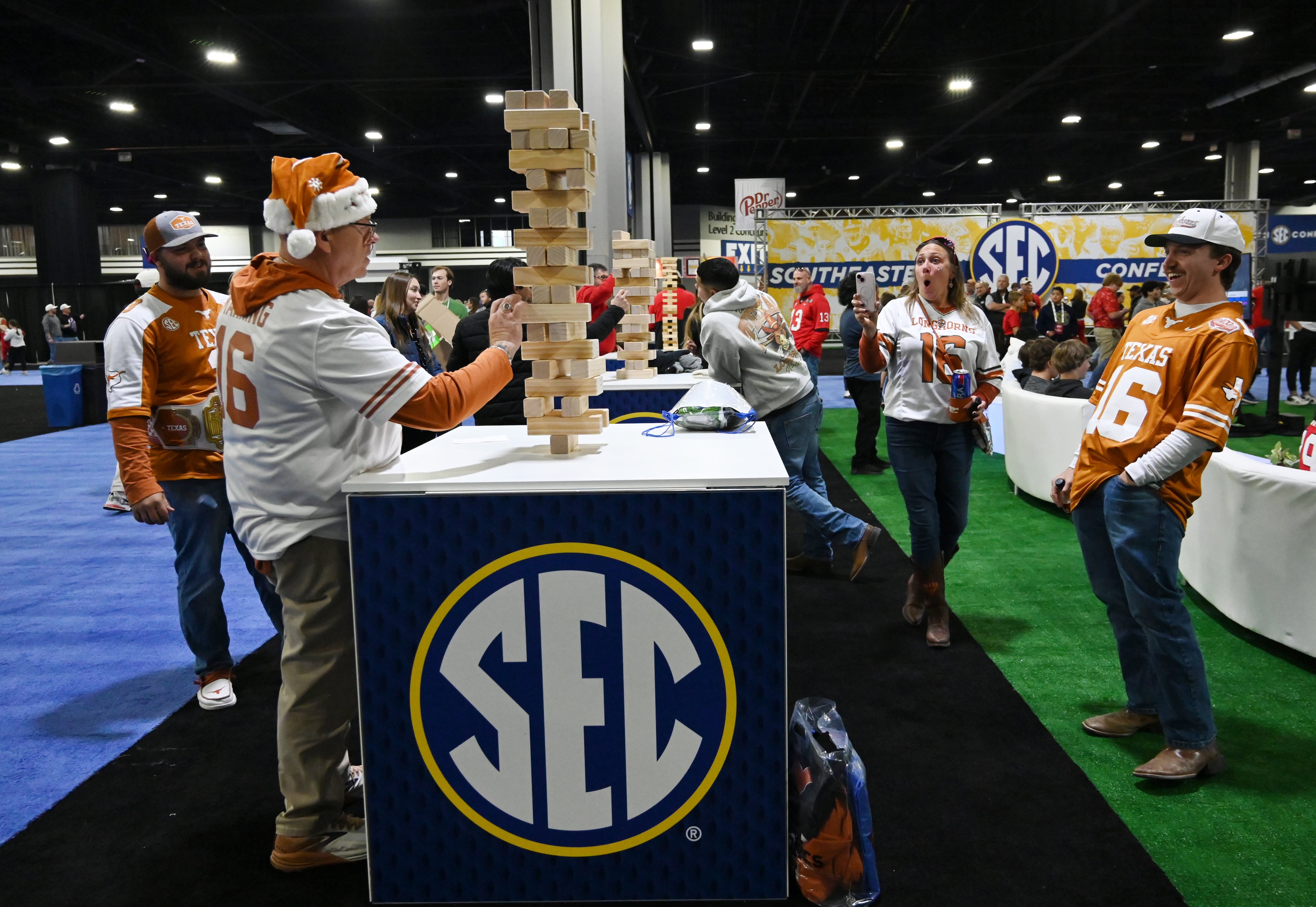 Texas fan David Paratain (left), of Luling, Texas, plays jenga as his family cheers at The Dr Pepper SEC FanFare ahead of the SEC Championship football game between Georgia and Texas at the Mercedes-Benz Stadium, Saturday, December 7, 2024, in Atlanta. (Hyosub Shin / AJC)