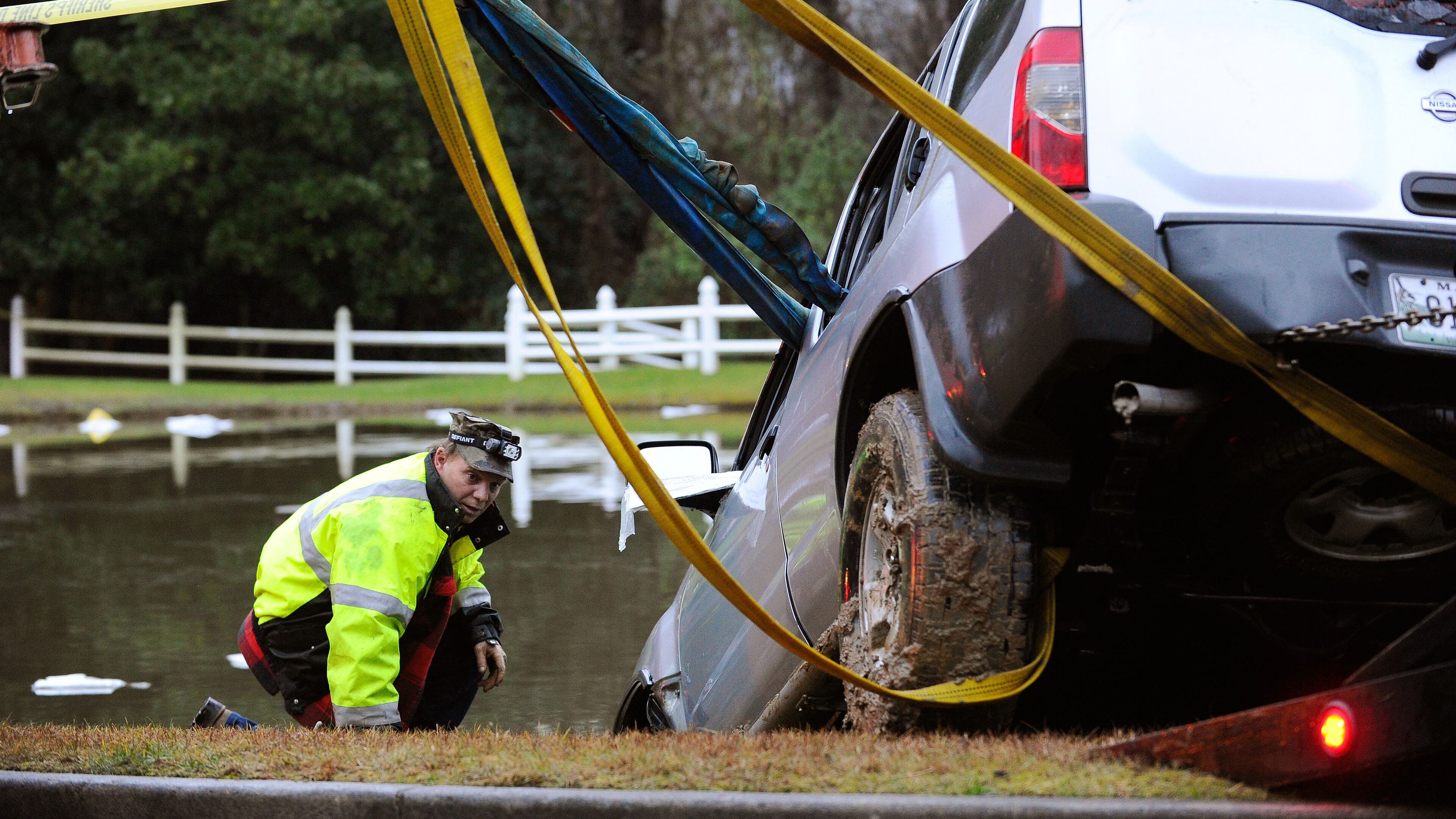 Officials help to remove an SUV that was submerged in a pond off Batesville Road in rural Cherokee County after a driver was rescued by firefighters near Atlanta National Golf Course early Monday morning, Dec. 29, 2014, in Canton.