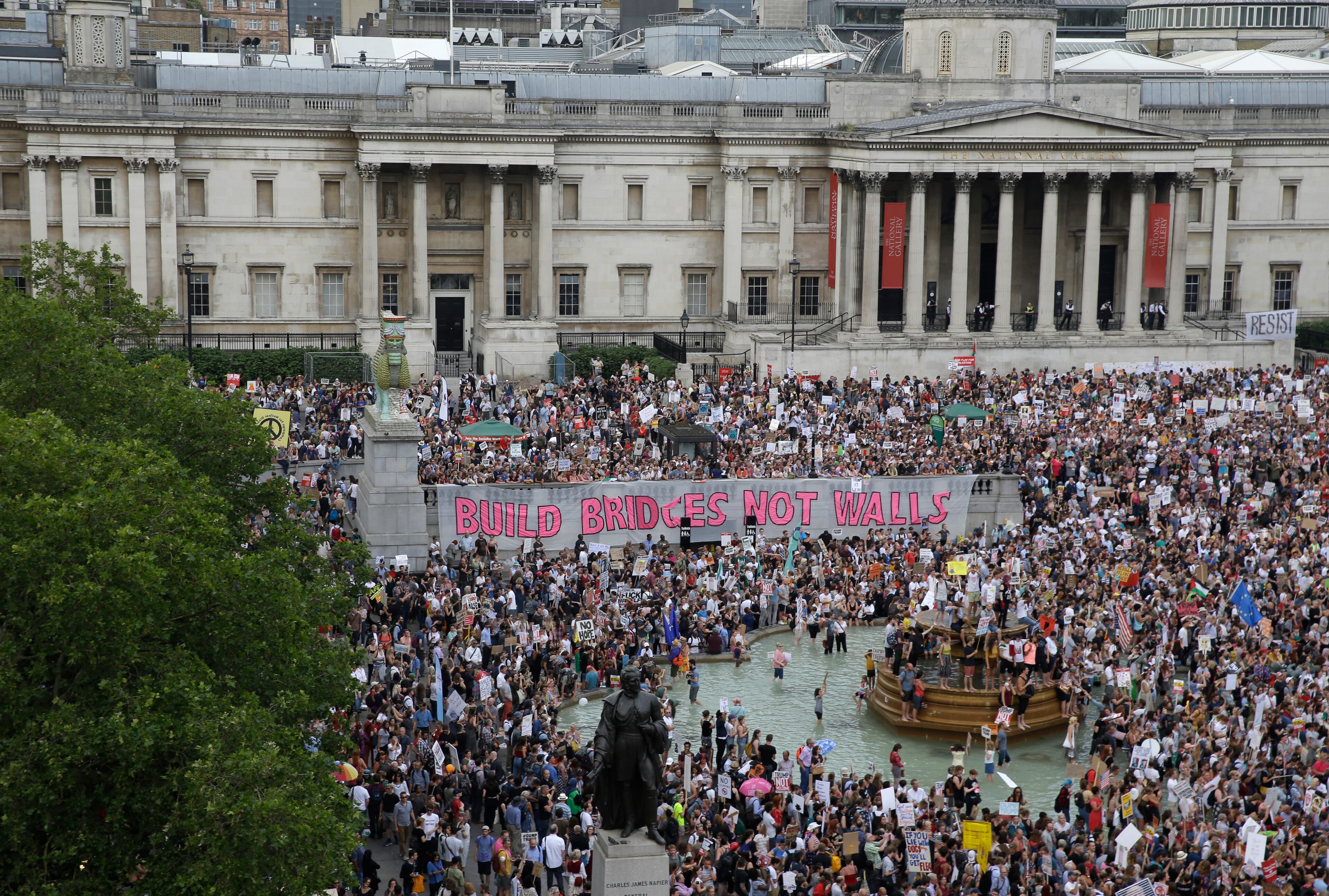 Protestors holding banners gather after a march opposed to the visit of U.S. President Donald Trump in Trafalgar Square in London, Friday, July 13, 2018. Trump's pomp-filled welcome to Britain was overshadowed Friday by an explosive interview in which he blasted Prime Minister Theresa May, blamed London's mayor for terror attacks against the city and argued that Europe was "losing its culture" because of immigration. (AP Photo/Luca Bruno)