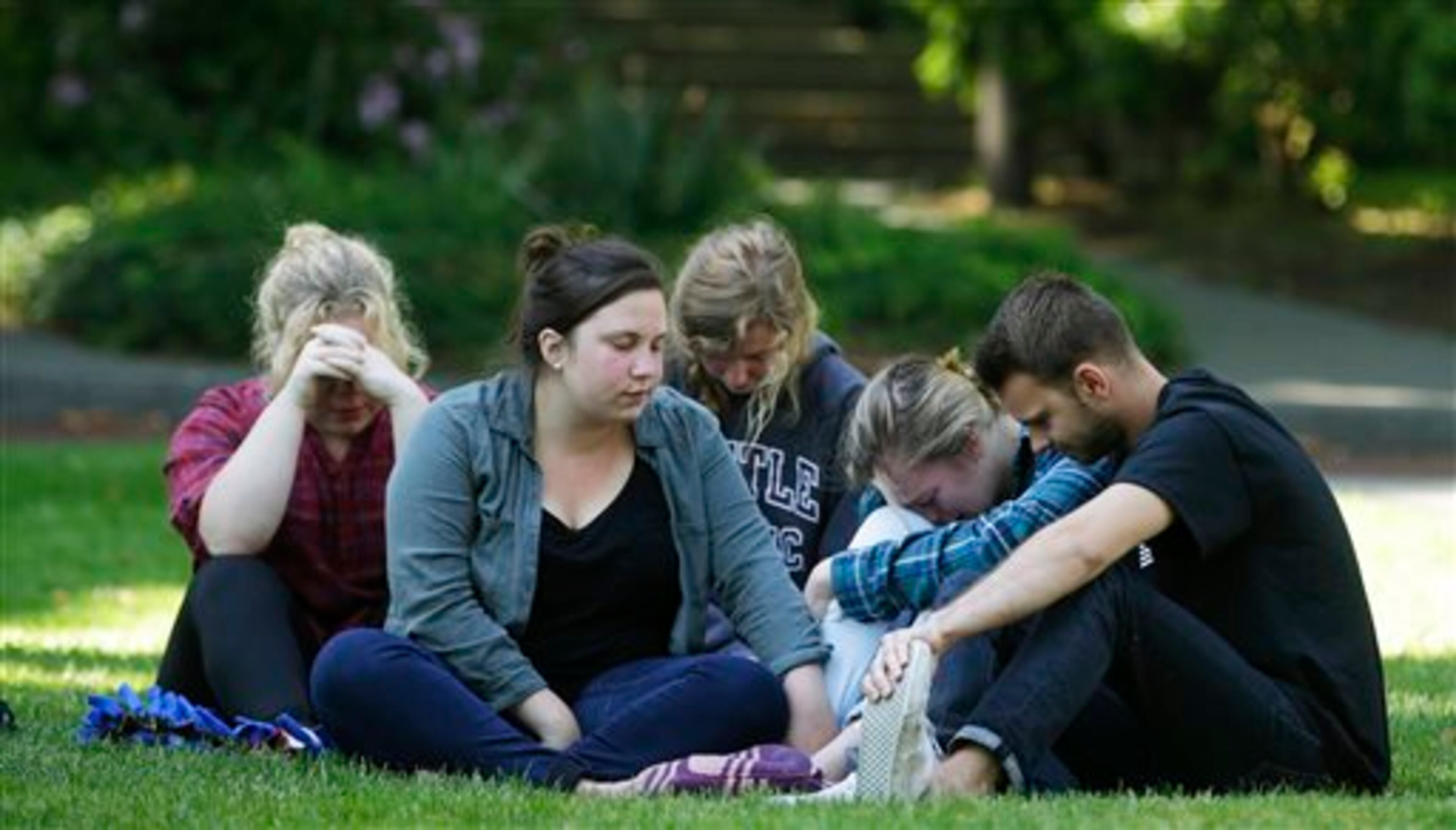 A group of people gather near a prayer circle on the campus of Seattle Pacific University, Friday, June 6, 2014 in Seattle. Classes were canceled Friday following a shooting at Otto Miller Hall Thursday afternoon. A 19-year-old man was fatally shot and two other young people were wounded after a gunman entered the foyer and started shooting. Aaron R. Ybarra, 26, was booked into the King County Jail late Thursday for investigation of homicide, according to police and the jail roster. (AP Photo/Ted S. Warren)