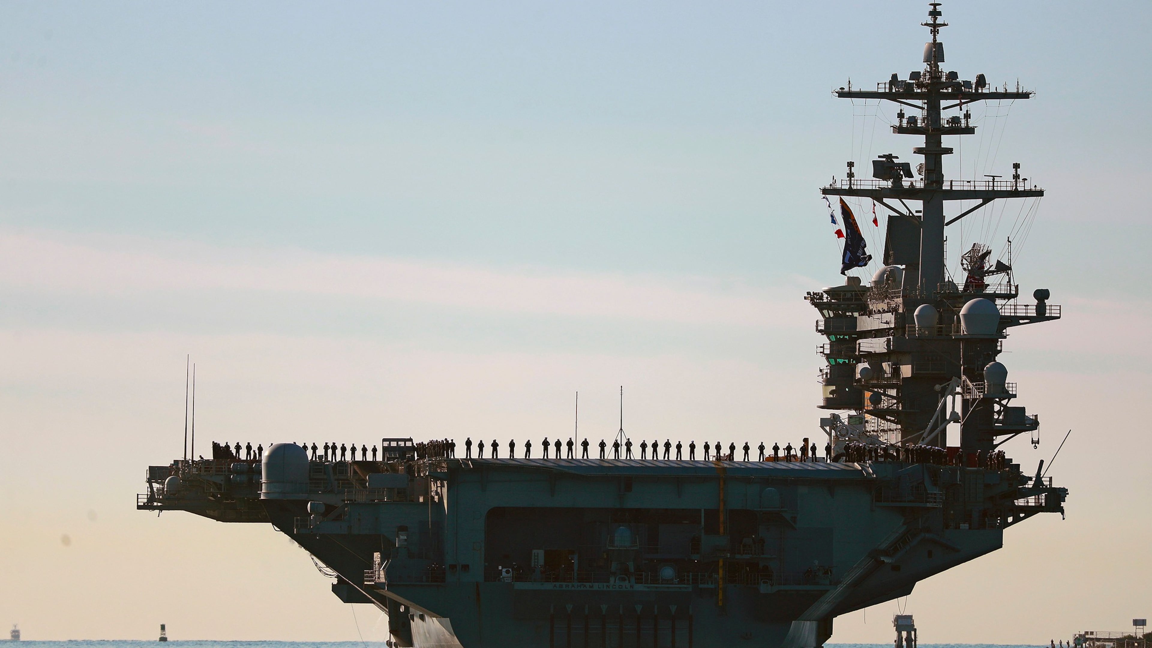 FILE - Sailors and marines line the deck of aircraft carrier USS Abraham Lincoln (CVN-72) as it deploys from San Diego,, Jan. 3, 2021. (K.C. Alfred/The San Diego Union-Tribune via AP, File)