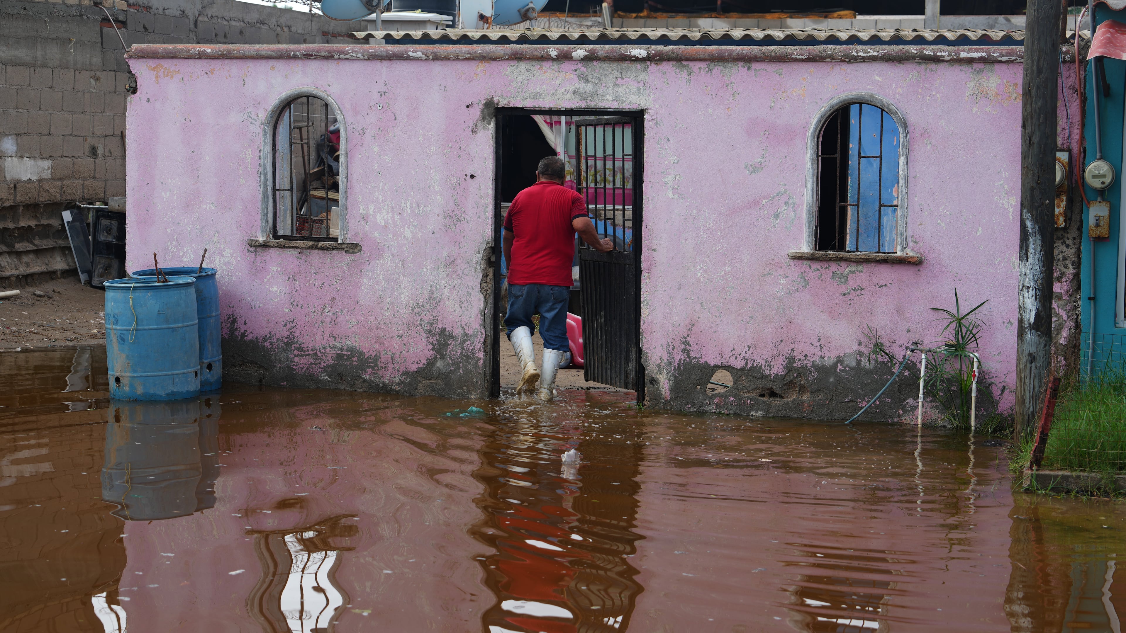 A resident enters his home surrounded by water brought by Hurricane Polo in Puerto San Carlos, Baja California Sur state, Mexico, Tuesday, Sept. 29, 2026. (AP Photo/Eduardo Verdugo)