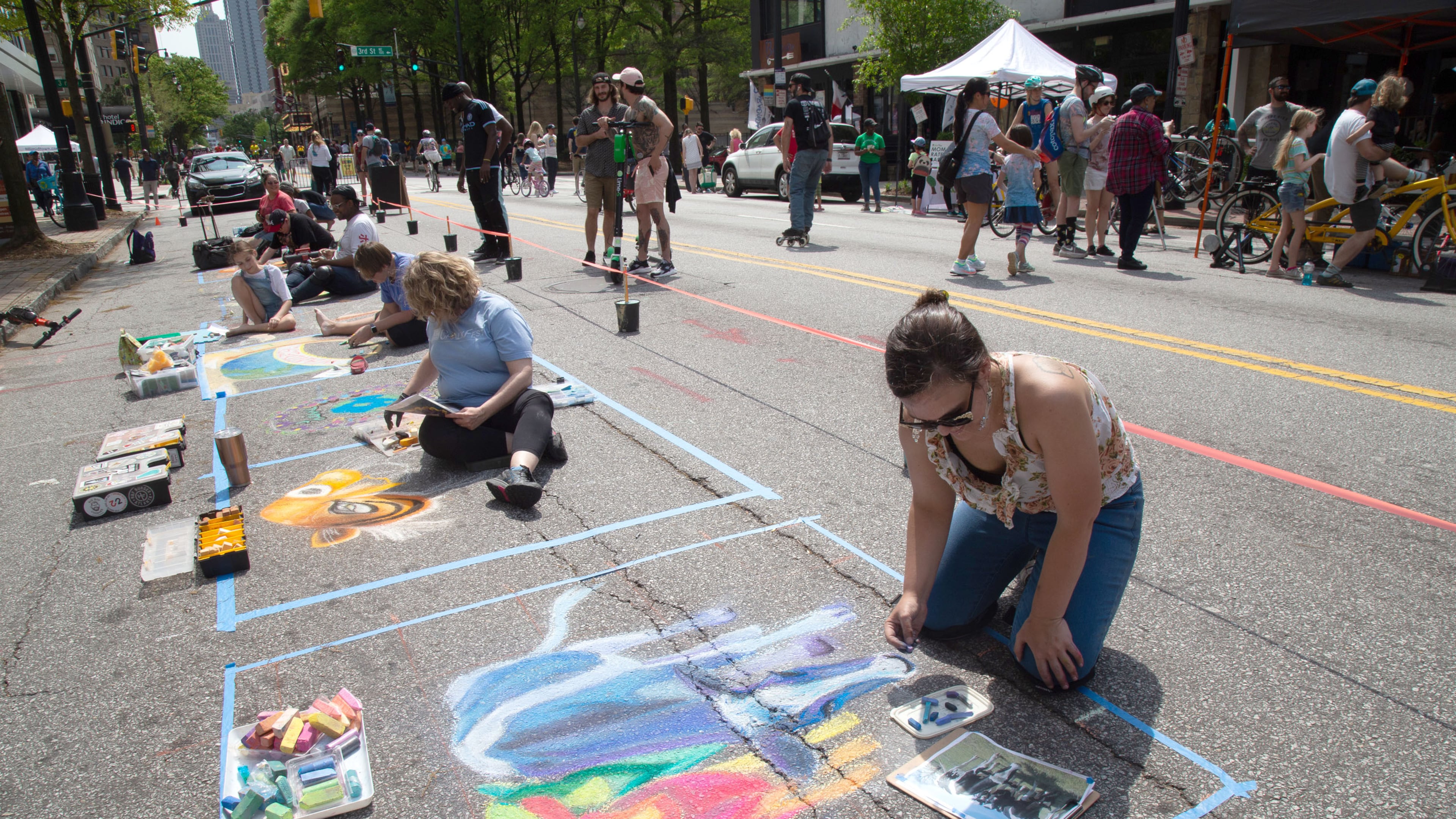Victoria Slagle makes a chalk drawing of cows on the side of Peachtree Stree during the Atlanta Streets Alive on Sunday, April 7, 2019. STEVE SCHAEFER / SPECIAL TO THE AJC