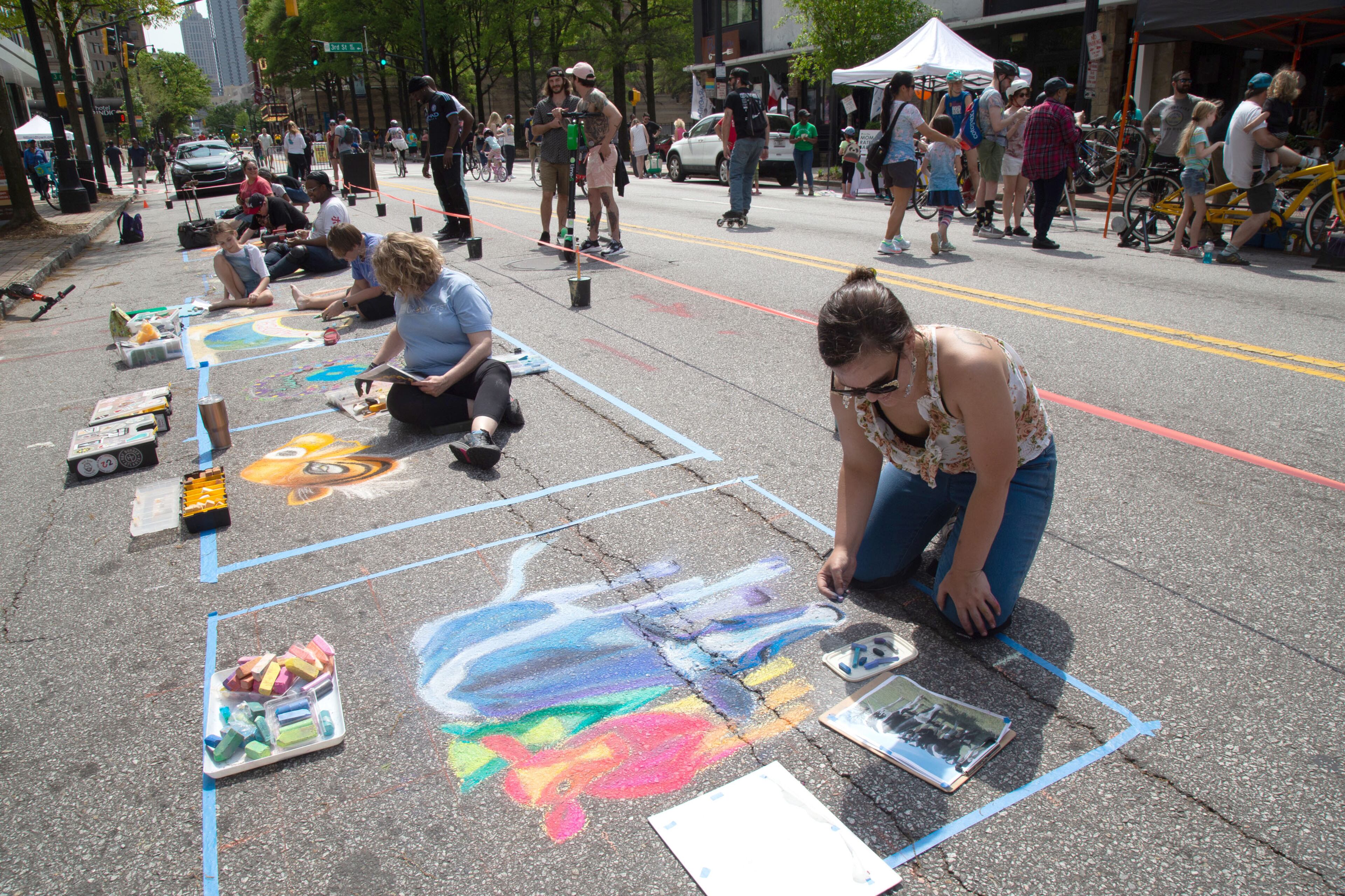 Victoria Slagle makes a chalk drawing of cows on the side of Peachtree Stree during the Atlanta Streets Alive on Sunday, April 7, 2019. STEVE SCHAEFER / SPECIAL TO THE AJC