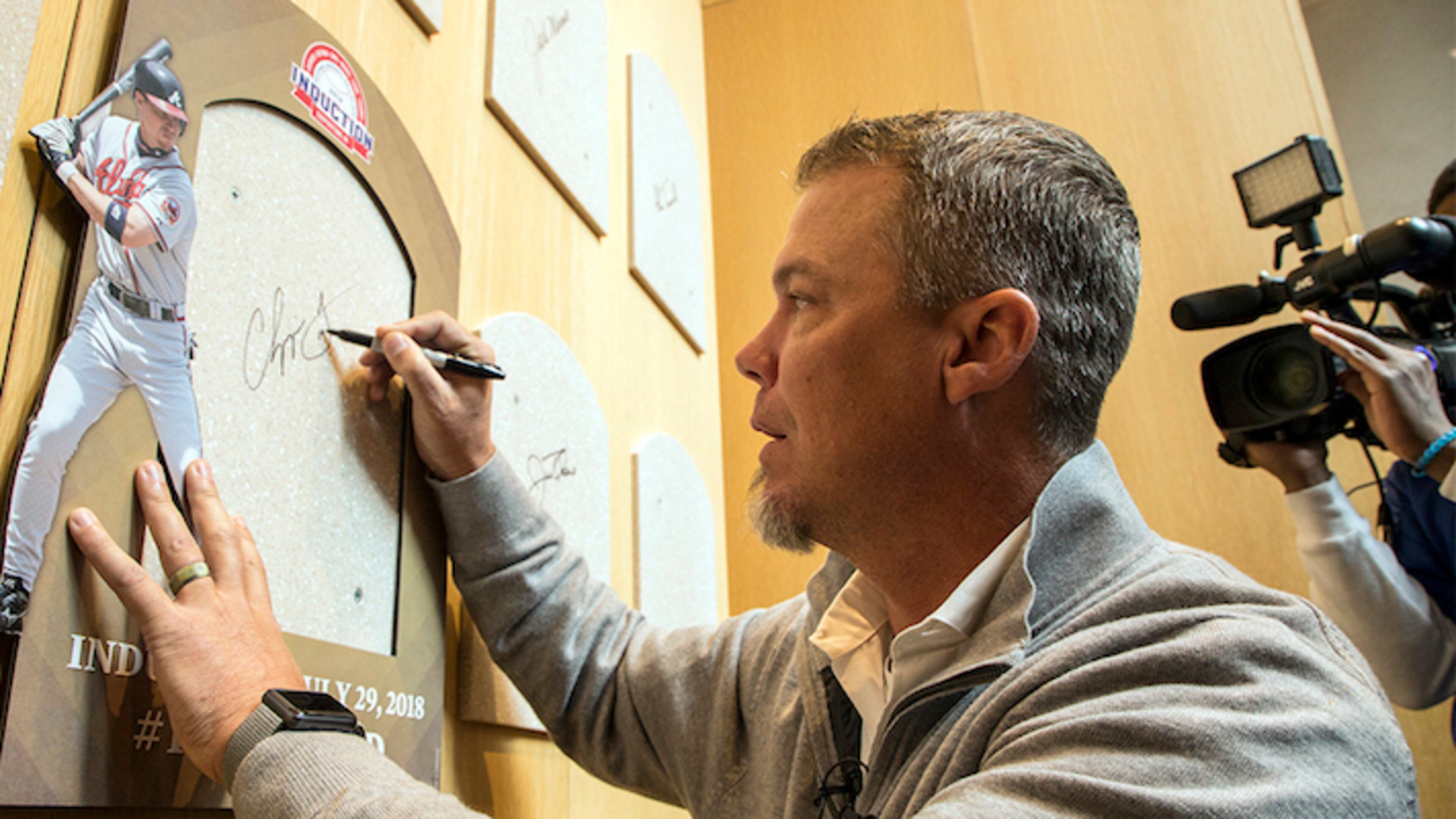 Hall of Fame inductee and former Atlanta Braves slugger Chipper Jones signs the spot where his Hall of Fame plaque will hang during an orientation tour of the National Baseball Hall of Fame in Cooperstown, N.Y., Tuesday, April 10, 2018. Jones toured the Hall of Fame to prepare for his induction this summer when he will be inducted along with Jim Thome, Vladimir Guerrero, Trevor Hoffman, Alan Trammel and Jack Morris. (Milo Stewart Jr./National Baseball Hall of Fame and Museum via AP)