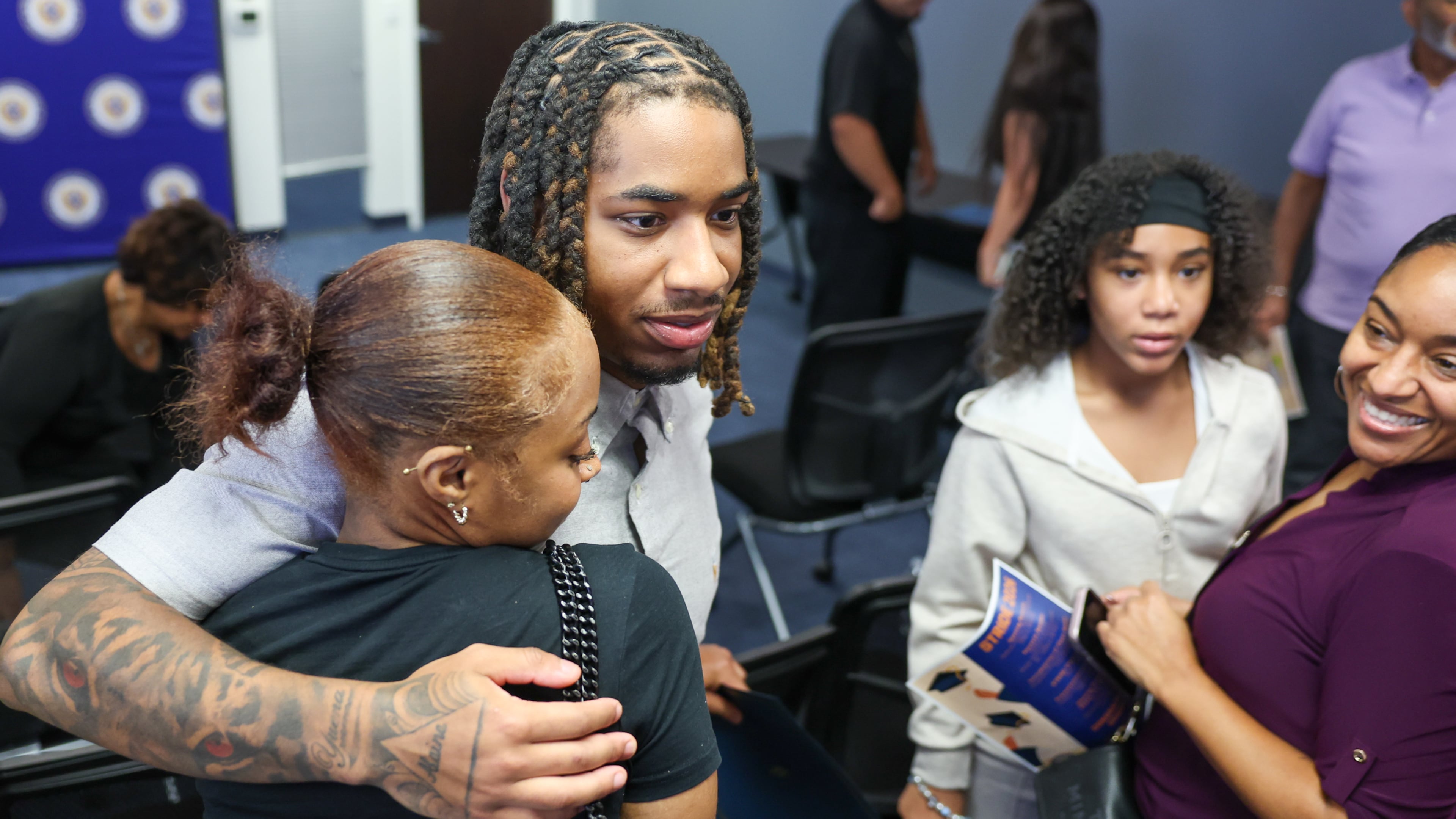 Valedictorian Amir Gilbert hugs his girlfriend Kailah Brown (from left), as his sister, Alaina Roberts, and mother, Yuena Perez, look on during the STRIDE graduation ceremony at the DeKalb County District Attorney’s Office on Monday, Sept. 28, 2026, in Decatur. (Arvin Temkar/AJC)