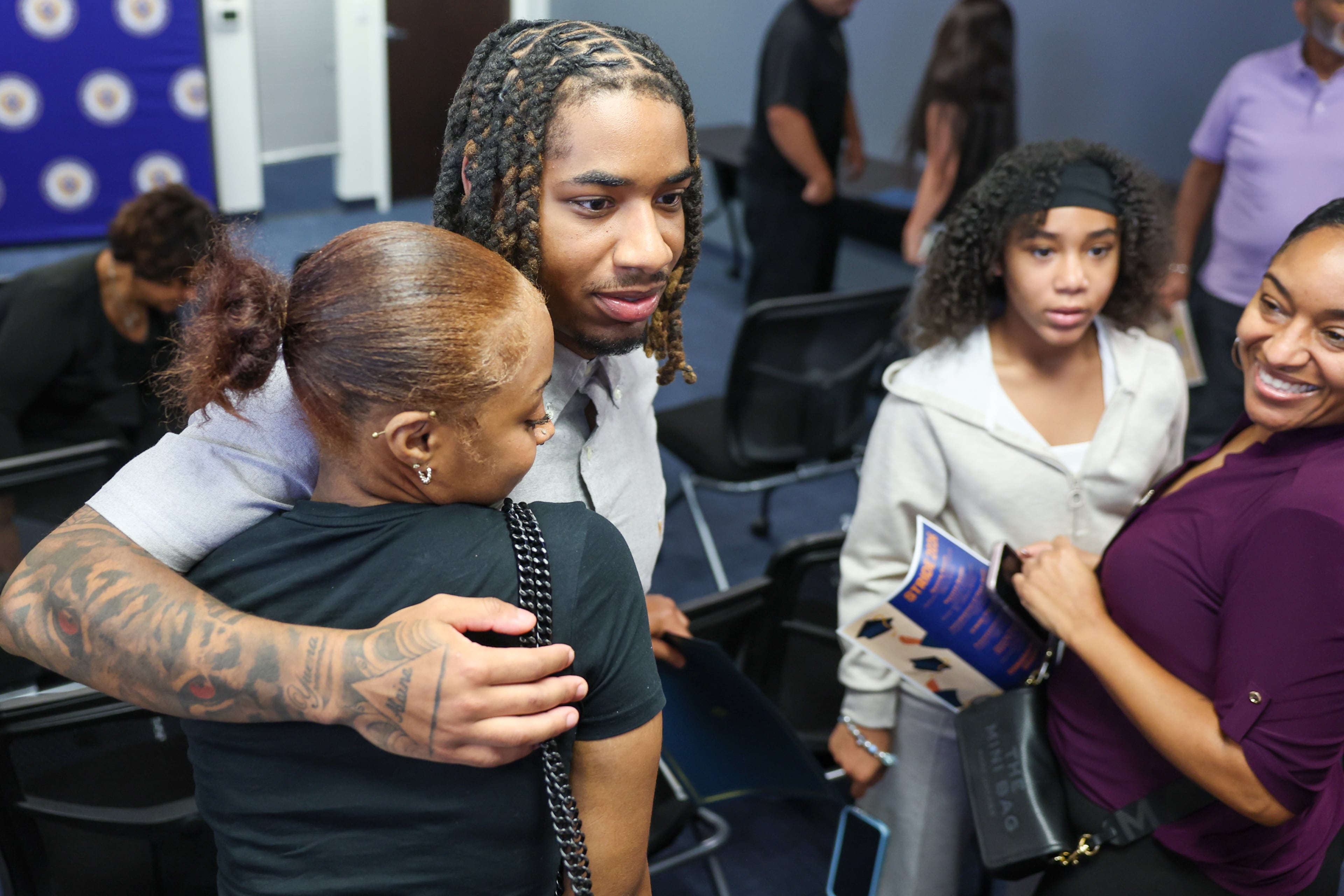 Valedictorian Amir Gilbert hugs his girlfriend Kailah Brown (from left), as his sister, Alaina Roberts, and mother, Yuena Perez, look on during the STRIDE graduation ceremony at the DeKalb County District Attorney’s Office on Monday, Sept. 28, 2026, in Decatur. (Arvin Temkar/AJC)