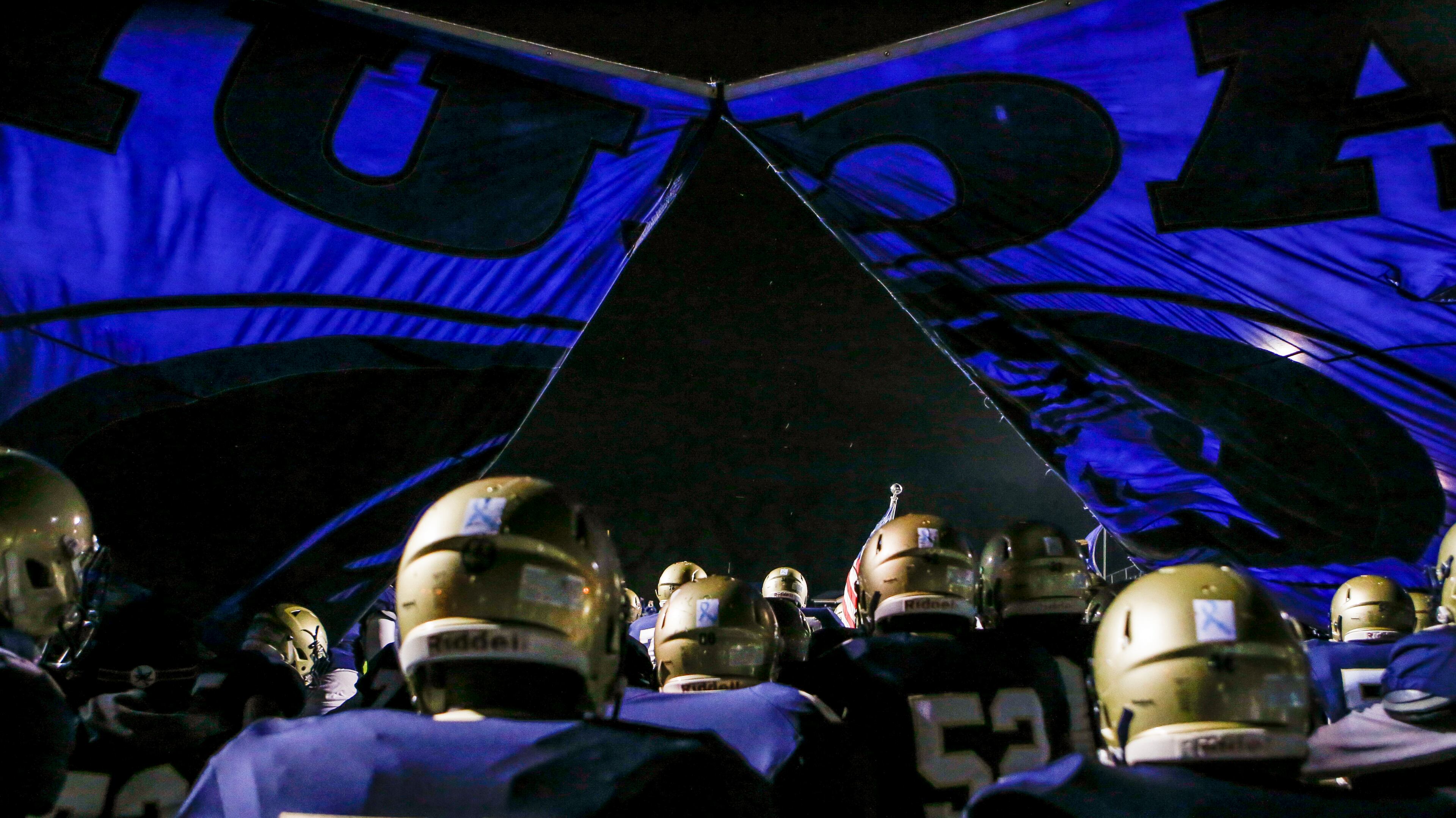 Members of the Dacula varsity football team break through their banner and run onto the field before the start of a high school football game. (Casey Sykes for the AJC)
