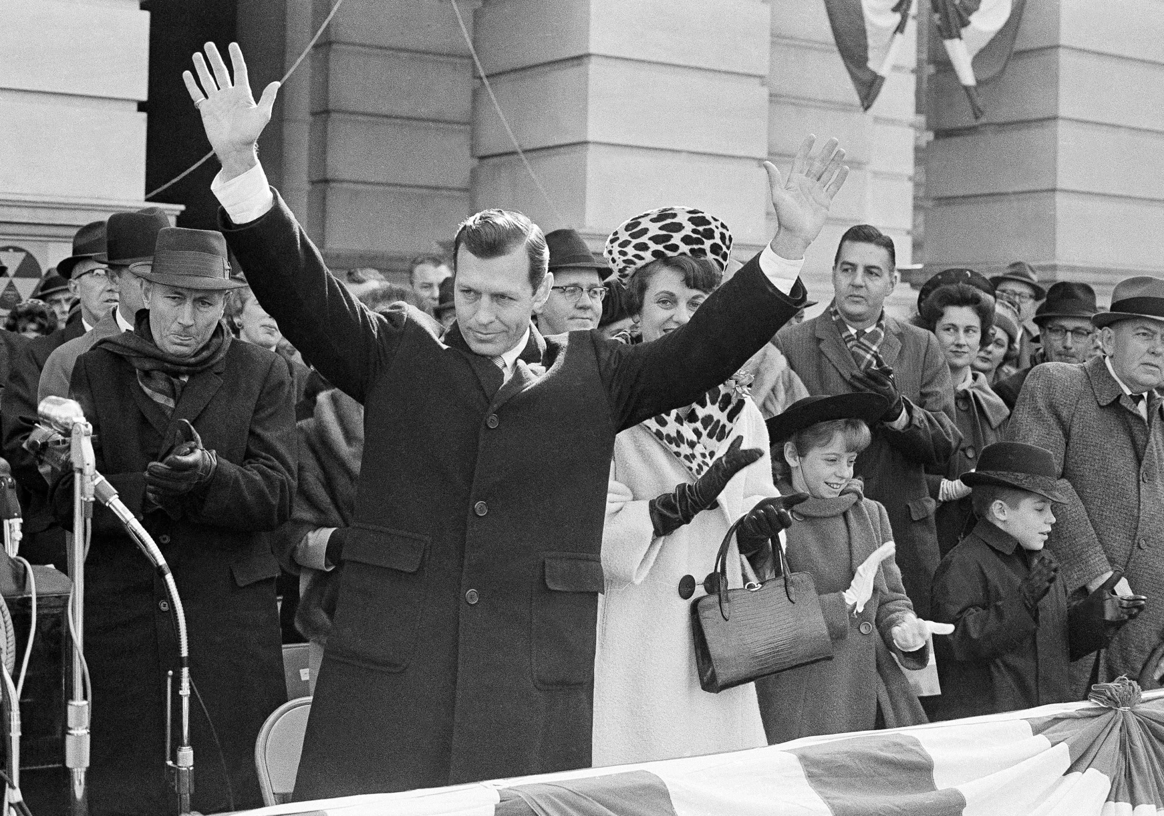 The crowd applauds as Carl Sanders raises hands in greeting after he was sworn in as governor of Georgia in ceremonies in Atlanta on Jan. 15, 1963. His wife, Betty, is at his side. Their two children at right are Carl Jr., and Betty. (AP Photo)