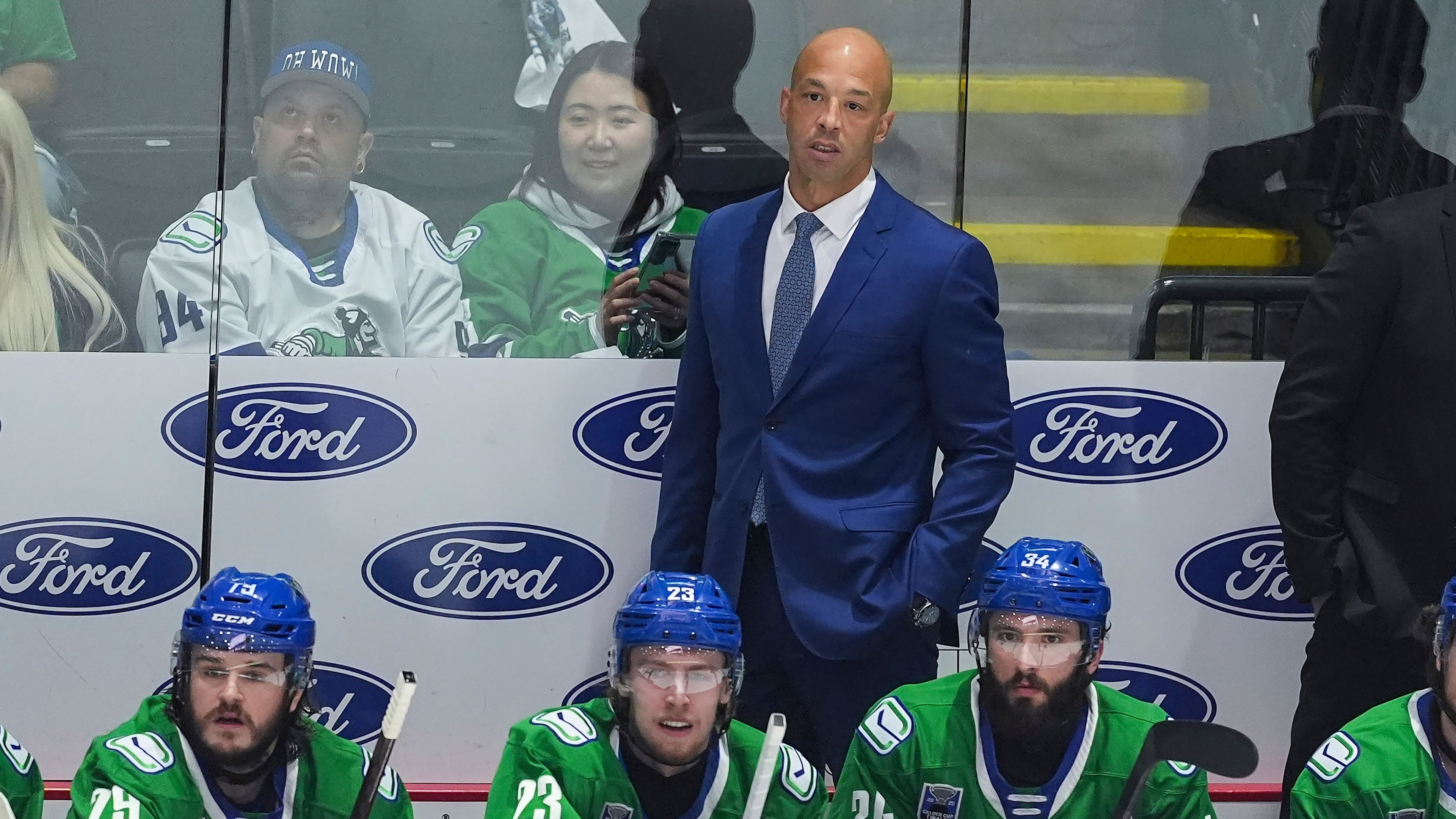 FILE -Abbotsford Canucks' head coach Manny Malhotra stands on the bench behind Sammy Blais, front left to right, Jonathan Lekkerimaki and Phillip Di Giuseppe during the first period in Game 5 of the AHL hockey Calder Cup Final against the Charlotte Checkers, in Abbotsford, British Columbia, June 21, 2025. (Darryl Dyck/The Canadian Press via AP, File)