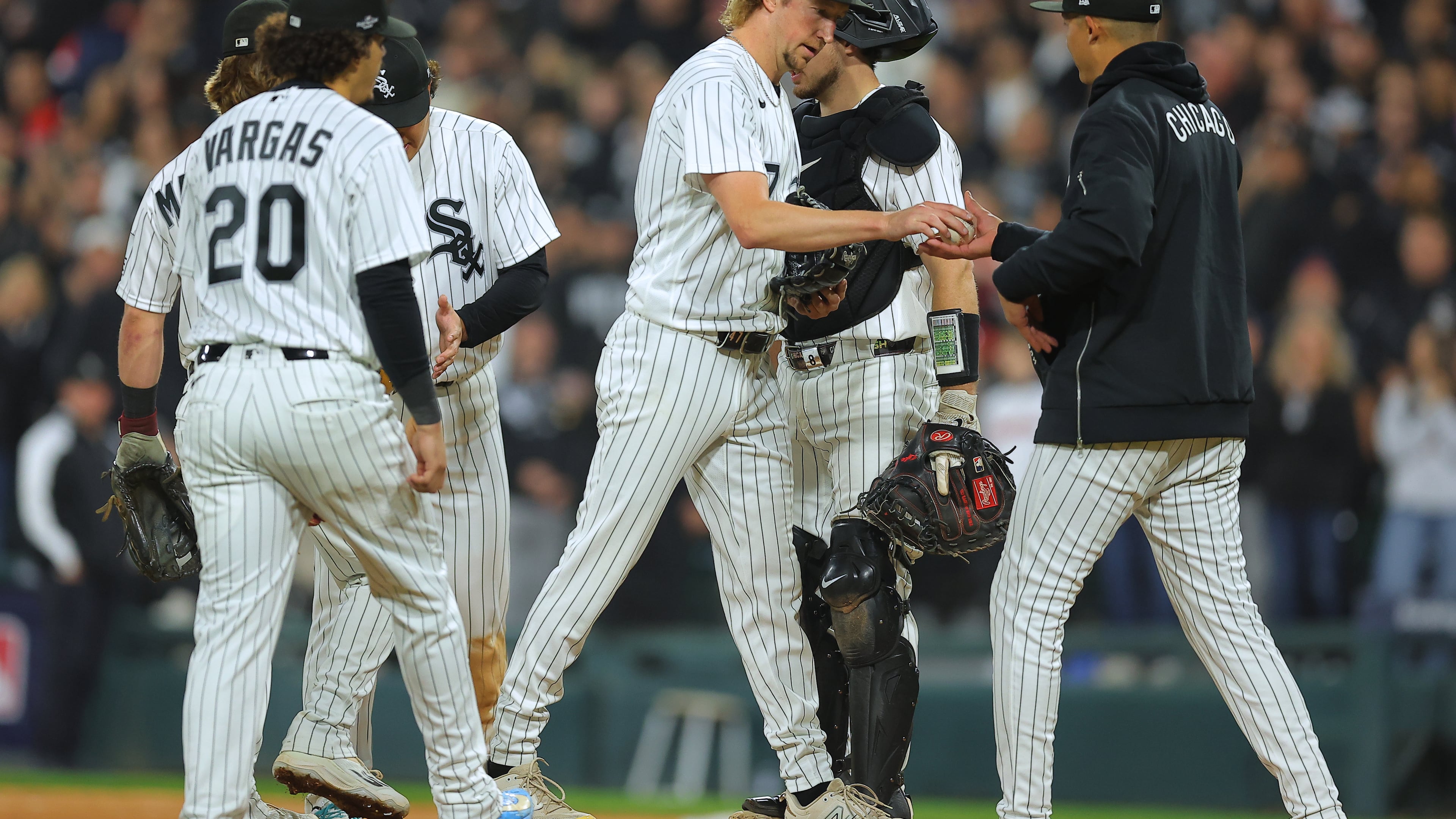 Chicago White Sox relief pitcher Erick Fedde, middle, hands the game ball to manager Will Venable, right, for a pitching change during the fifth inning of Game 4 of baseball's American League Division Series against the Cleveland Guardians, Thursday, Oct. 8, 2026, in Chicago. (AP Photo/Melissa Tamez)