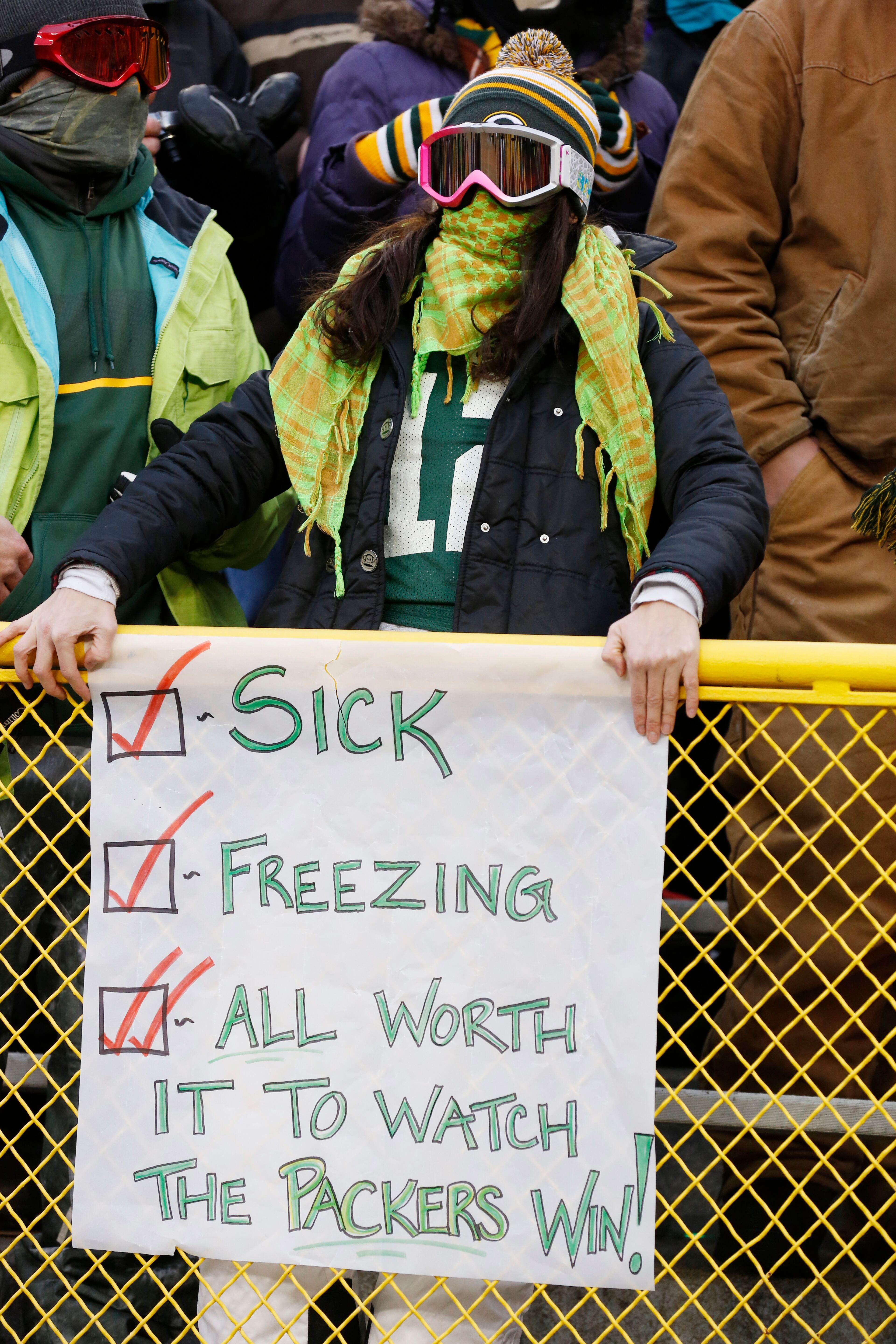 A fan stands behind a sign during the first half of an NFL wild-card playoff football game, Sunday, Jan. 5, 2014, in Green Bay, Wis.