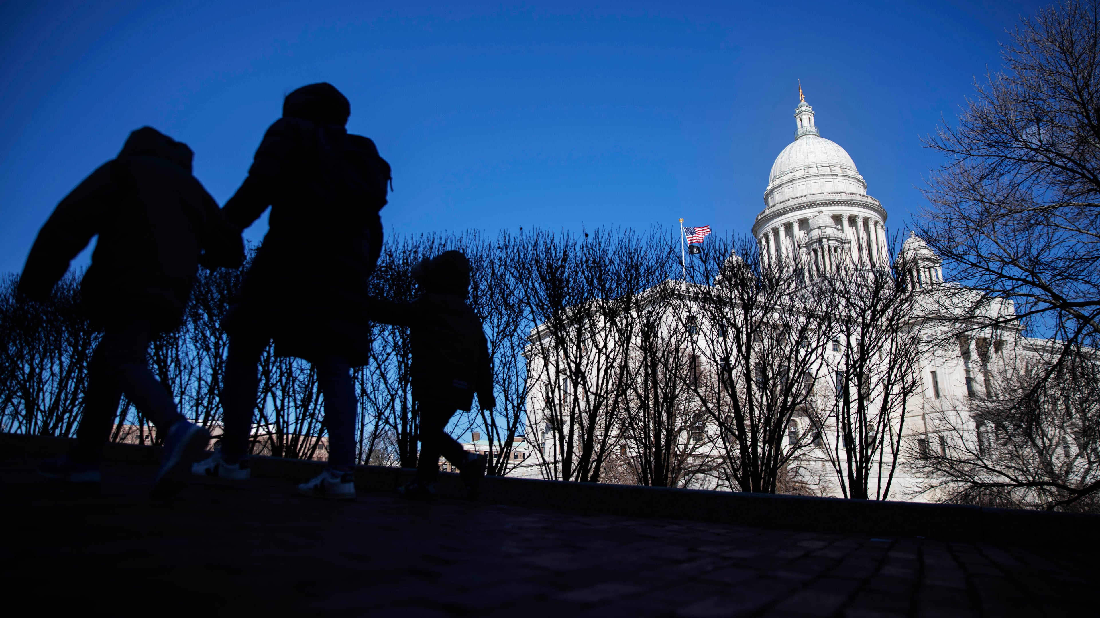 FILE - Pedestrians walk past the Rhode Island Statehouse, March 1, 2020, in Providence, R.I. (AP Photo/David Goldman, File)