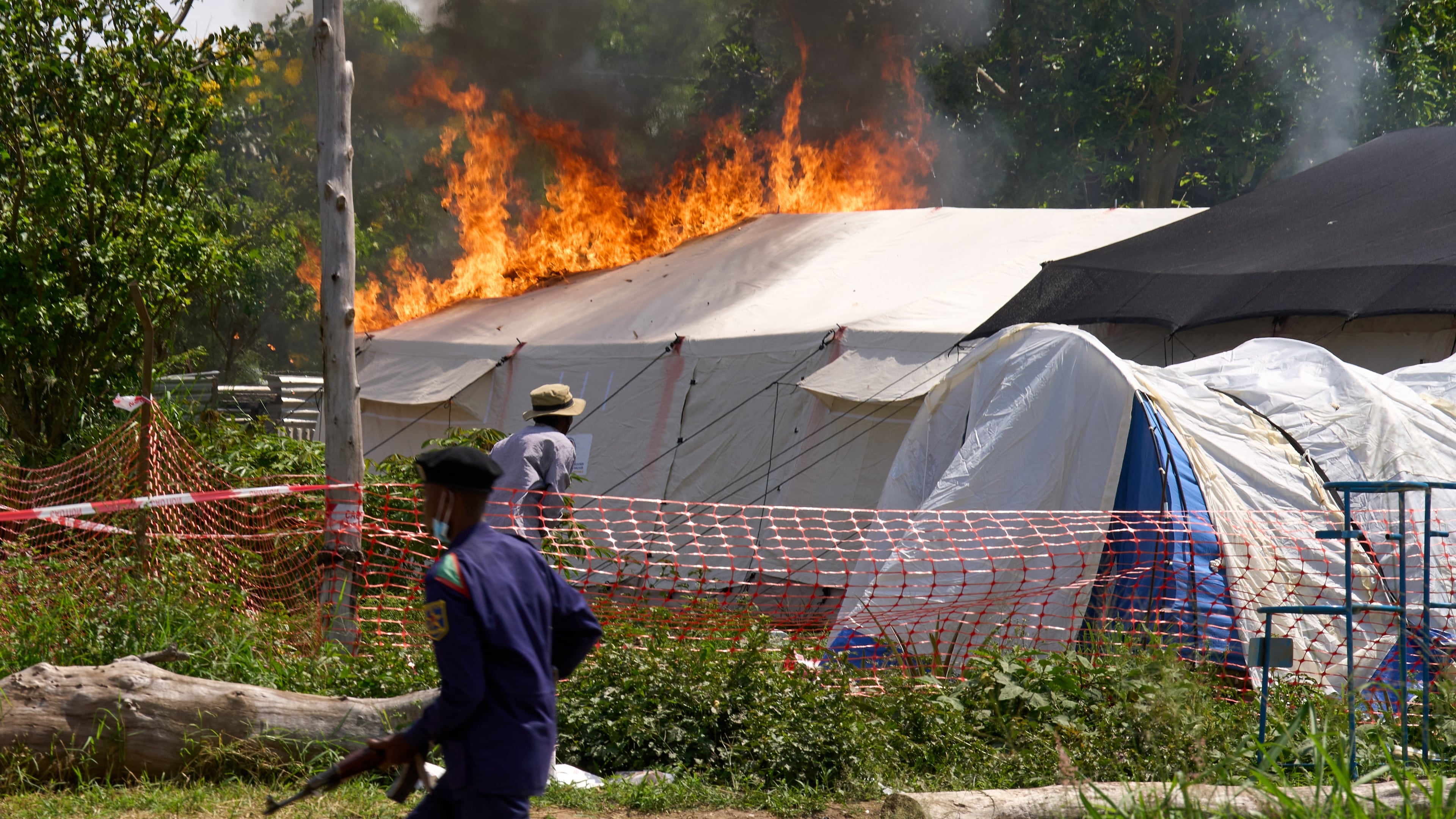 A security guard runs in front of an Ebola treatment center in flames in Rwampara, Congo, Thursday, May 21, 2026. (AP Photo/Dirole Lotsima Dieudonne)