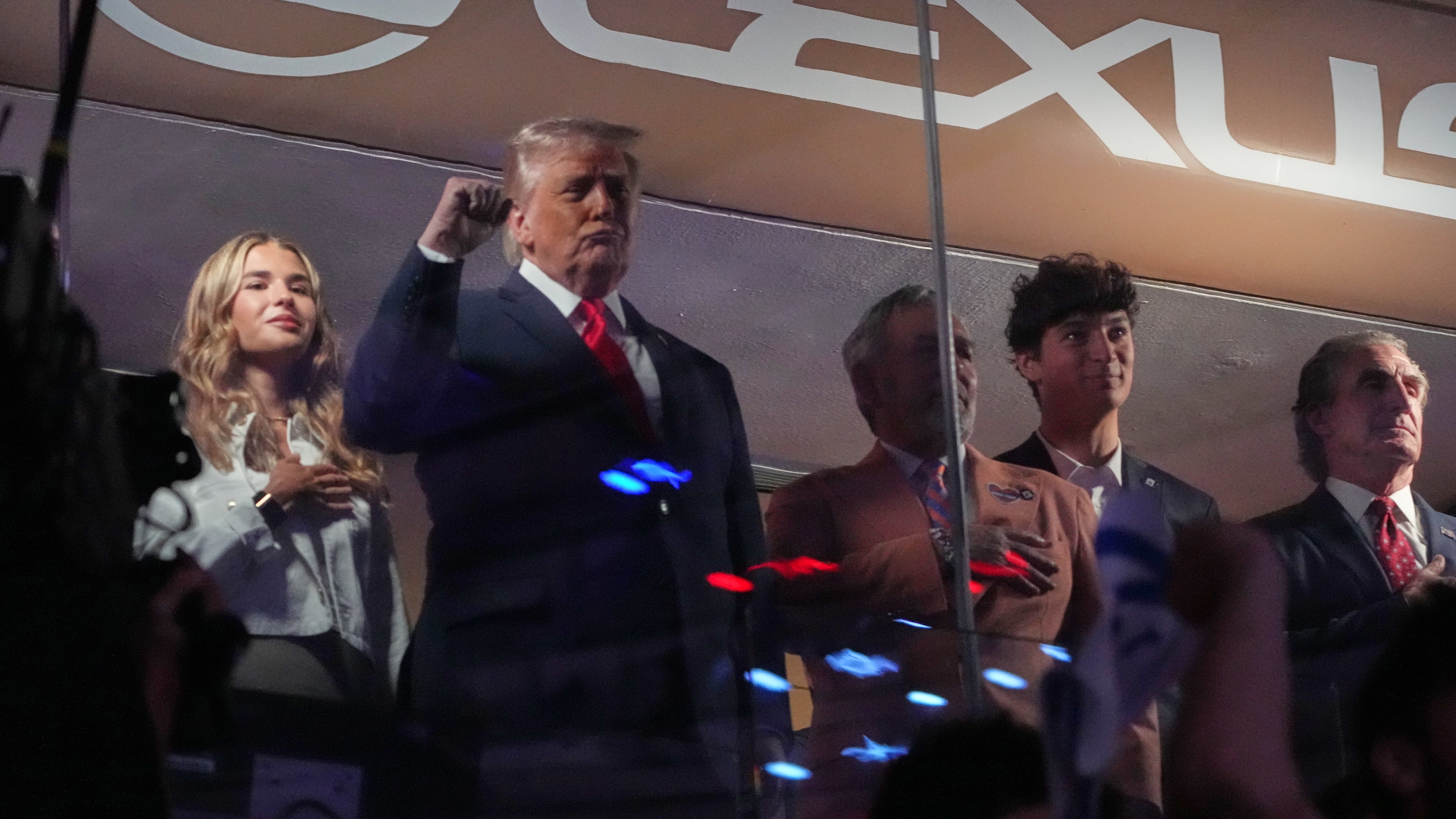 President Donald Trump gestures during the National Anthem as he attends an NBA Finals playoff basketball game between the New York Knicks and the San Antonio Spurs at Madison Square Garden in New York, Monday, June 8, 2026, with Kai Trump, left, Knicks owner James Dolan and Interior Secretary Doug Burgum, right. (AP Photo/Mark Schiefelbein)